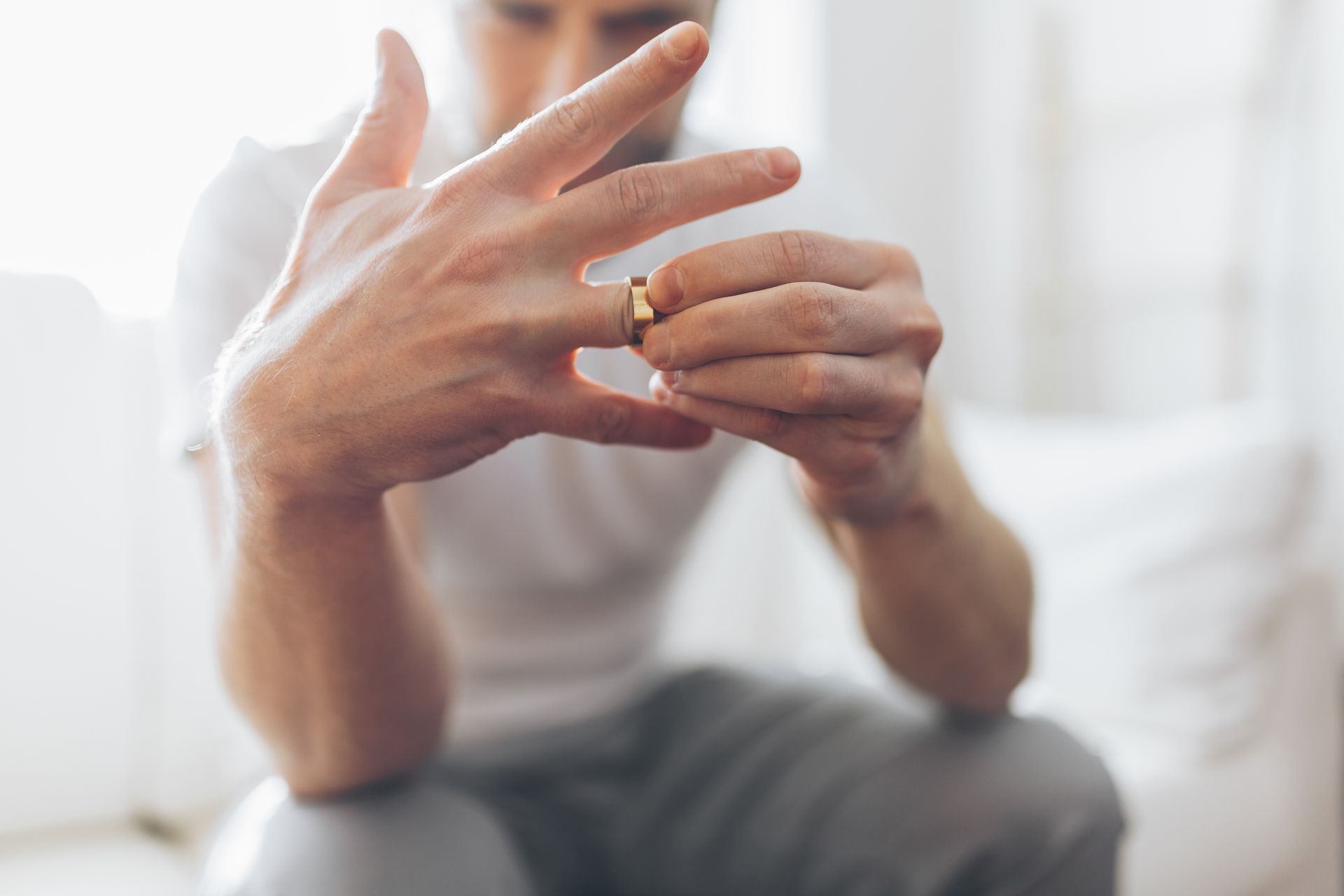 Heartbroken man holding a wedding ring.