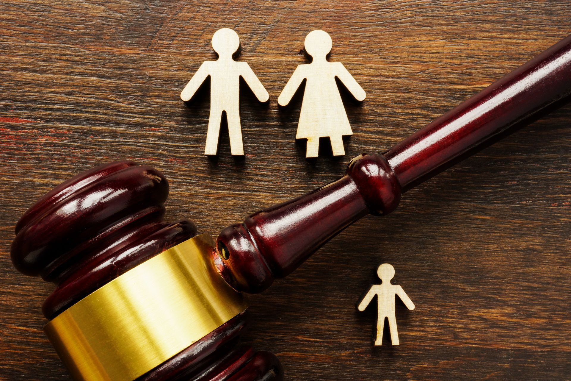 Wooden gavel beside family paper cutouts symbolizing justice and child custody law decision.