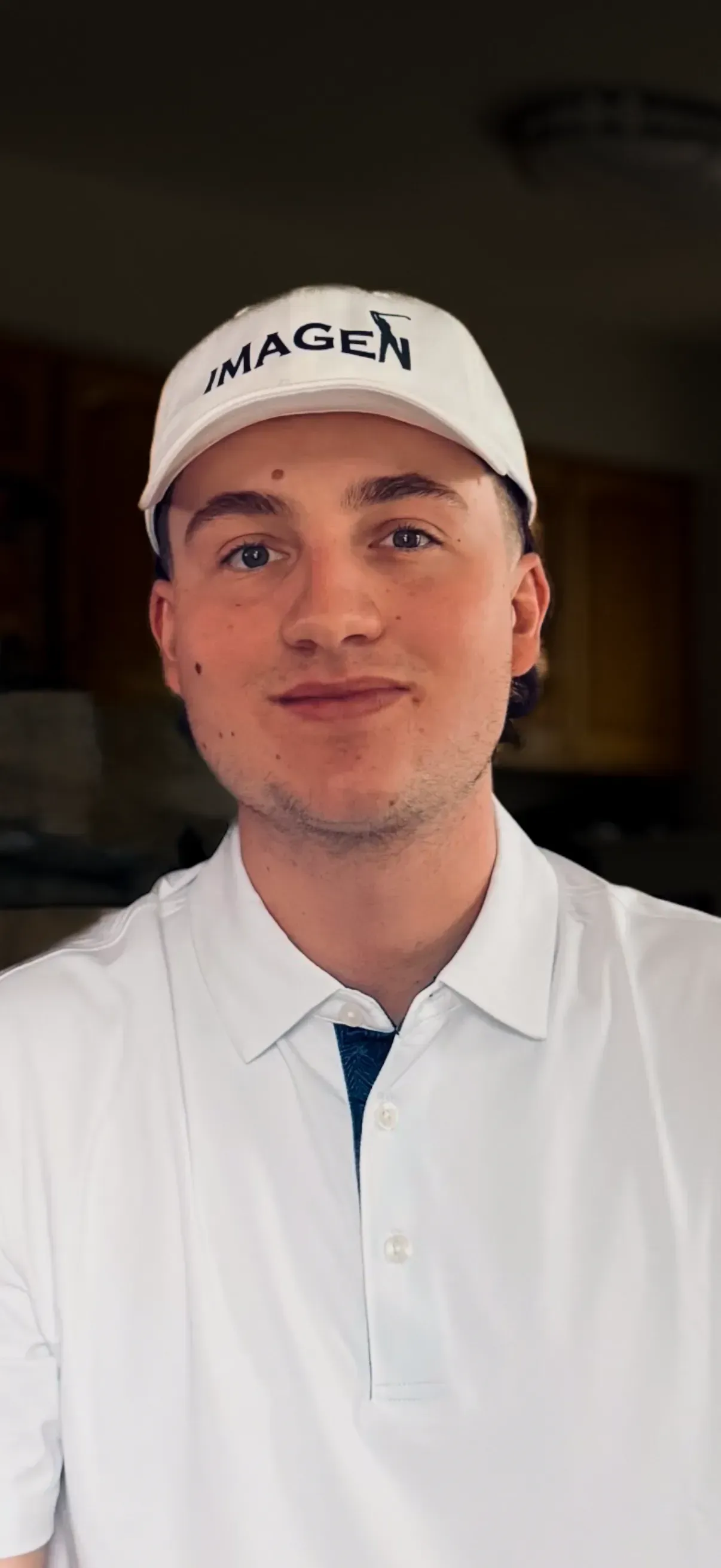 Person in a white coat and white cap, facing the camera indoors.