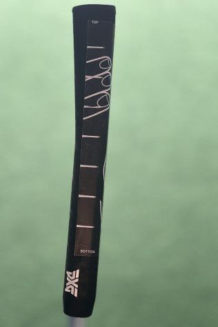 Black golf club cover with white stitching and small logo on a green background