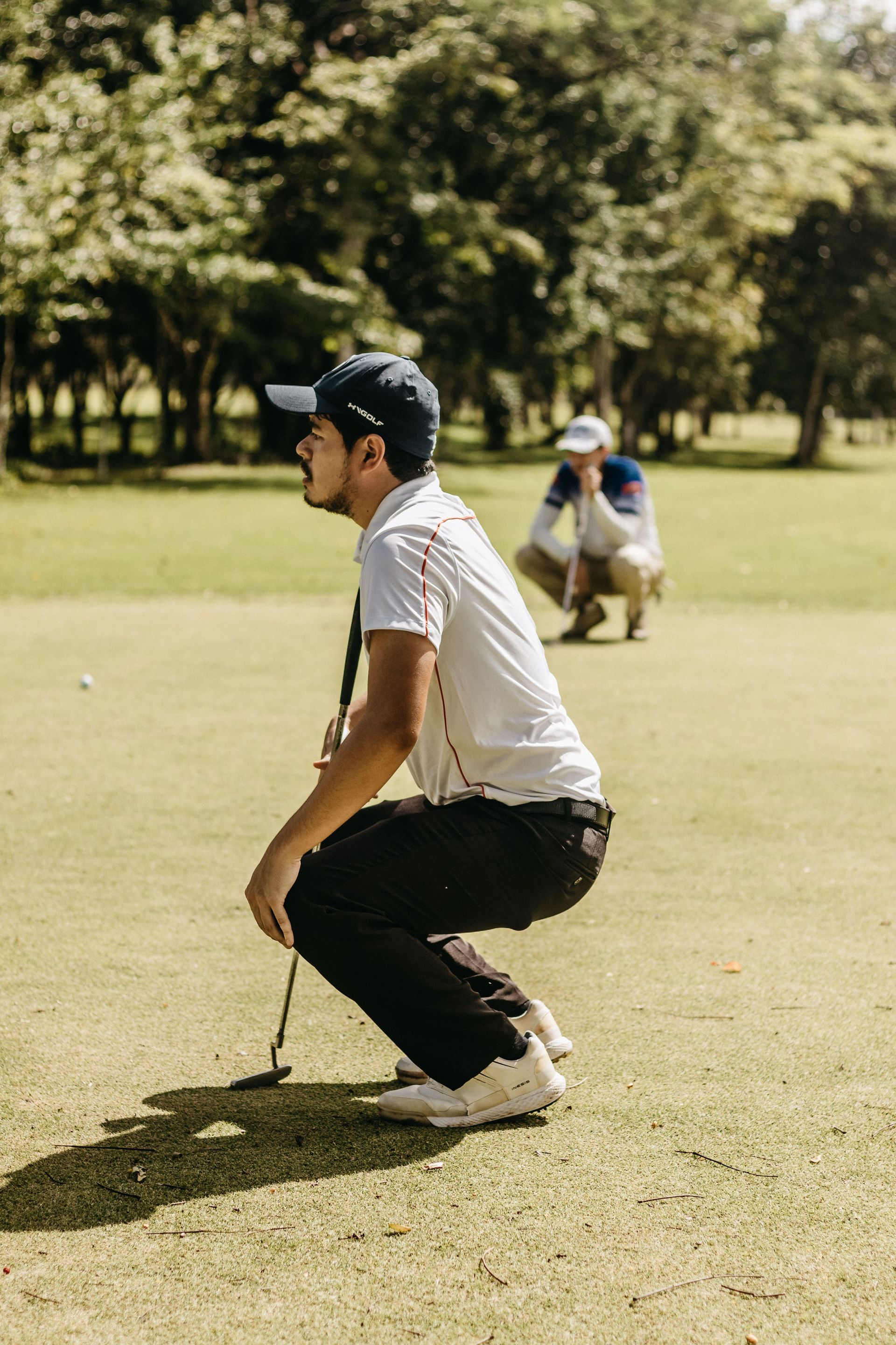 Golfers on a green shaking hands after a putt, with two others playing in the background.