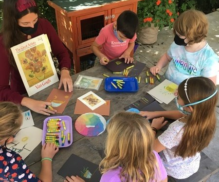 A group of children are sitting around a table with crayons and a book.