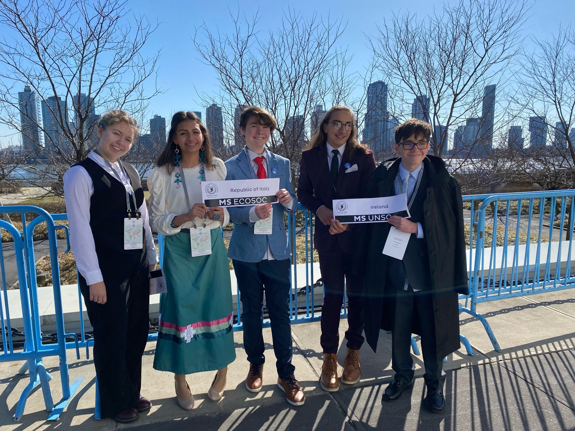 A group of children standing next to each other holding signs in front of a city skyline.