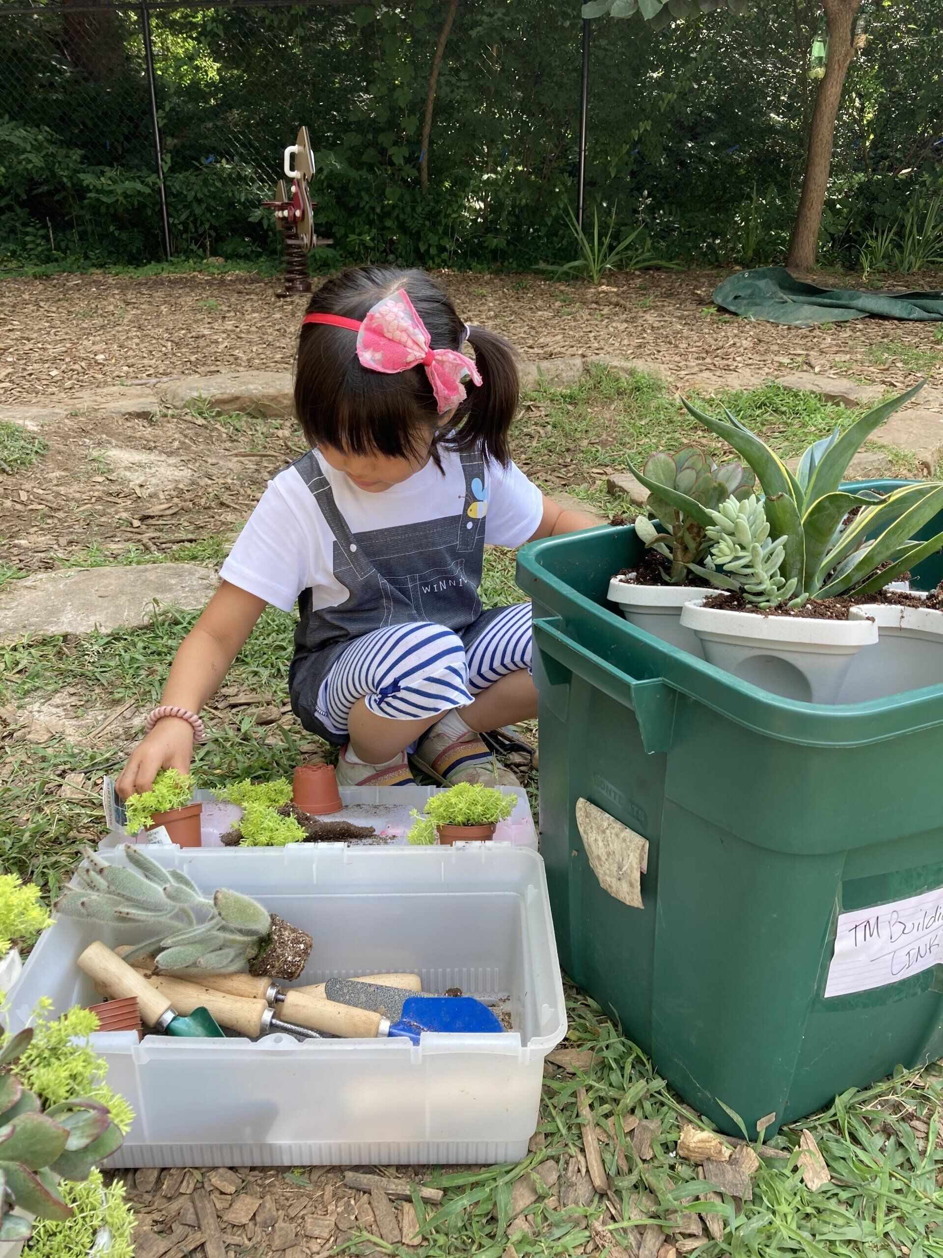 A little girl is playing with potted plants in a garden.