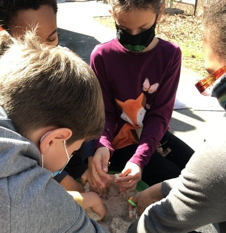 A group of children are siting on the ground in circle