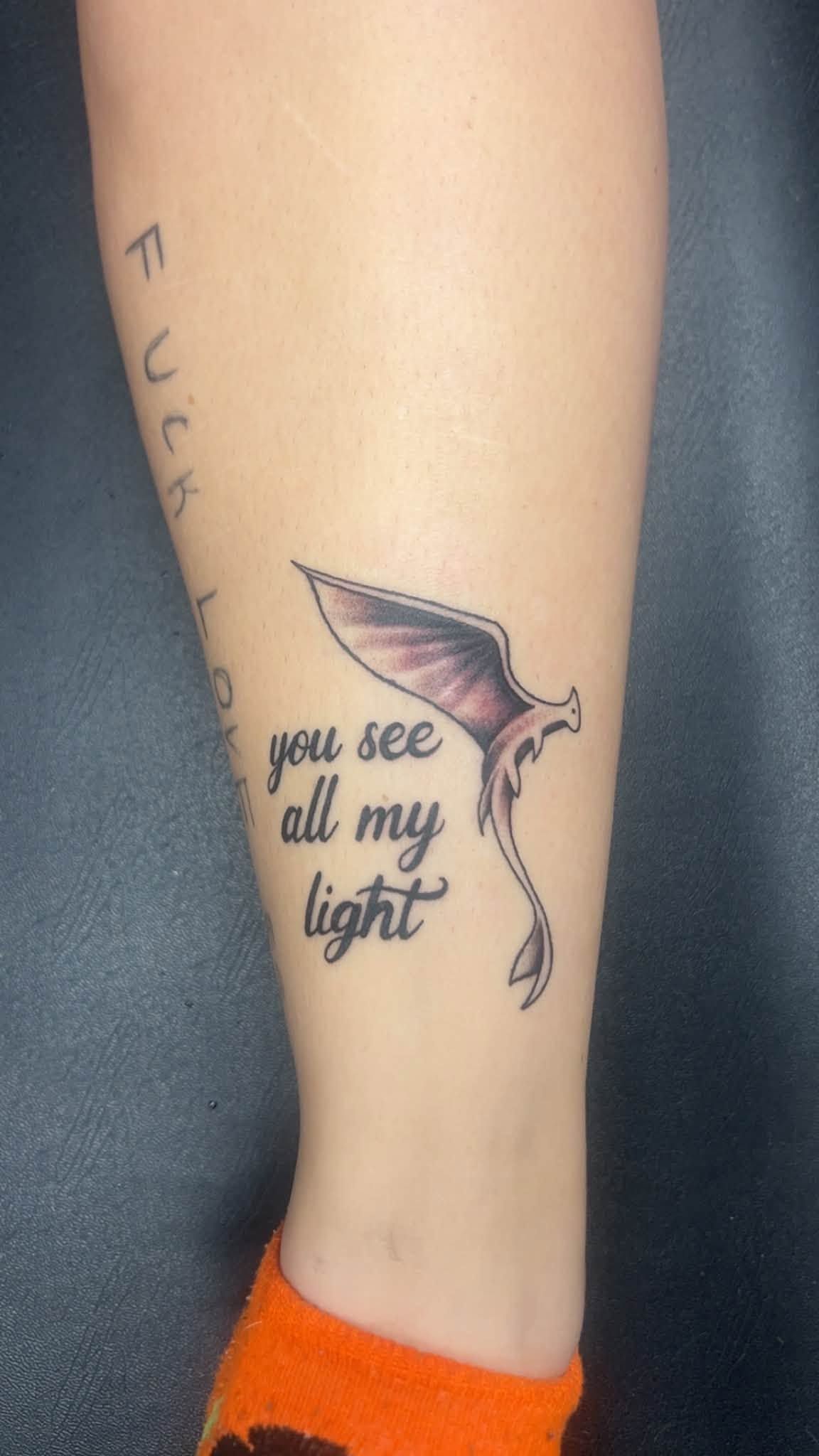 Lower leg with a small pink-and-black butterfly tattoo and the words “you see all my light”