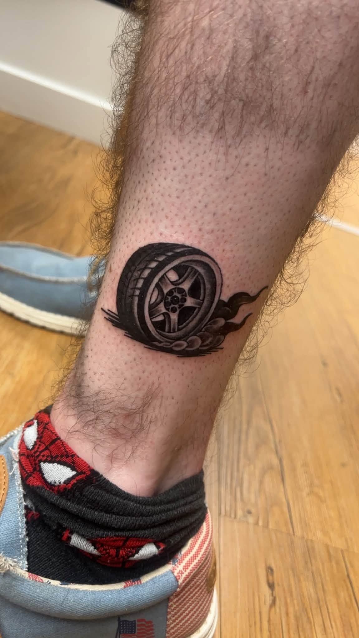 Close-up of a lower leg with a circular black tattoo near the ankle above a sneaker.