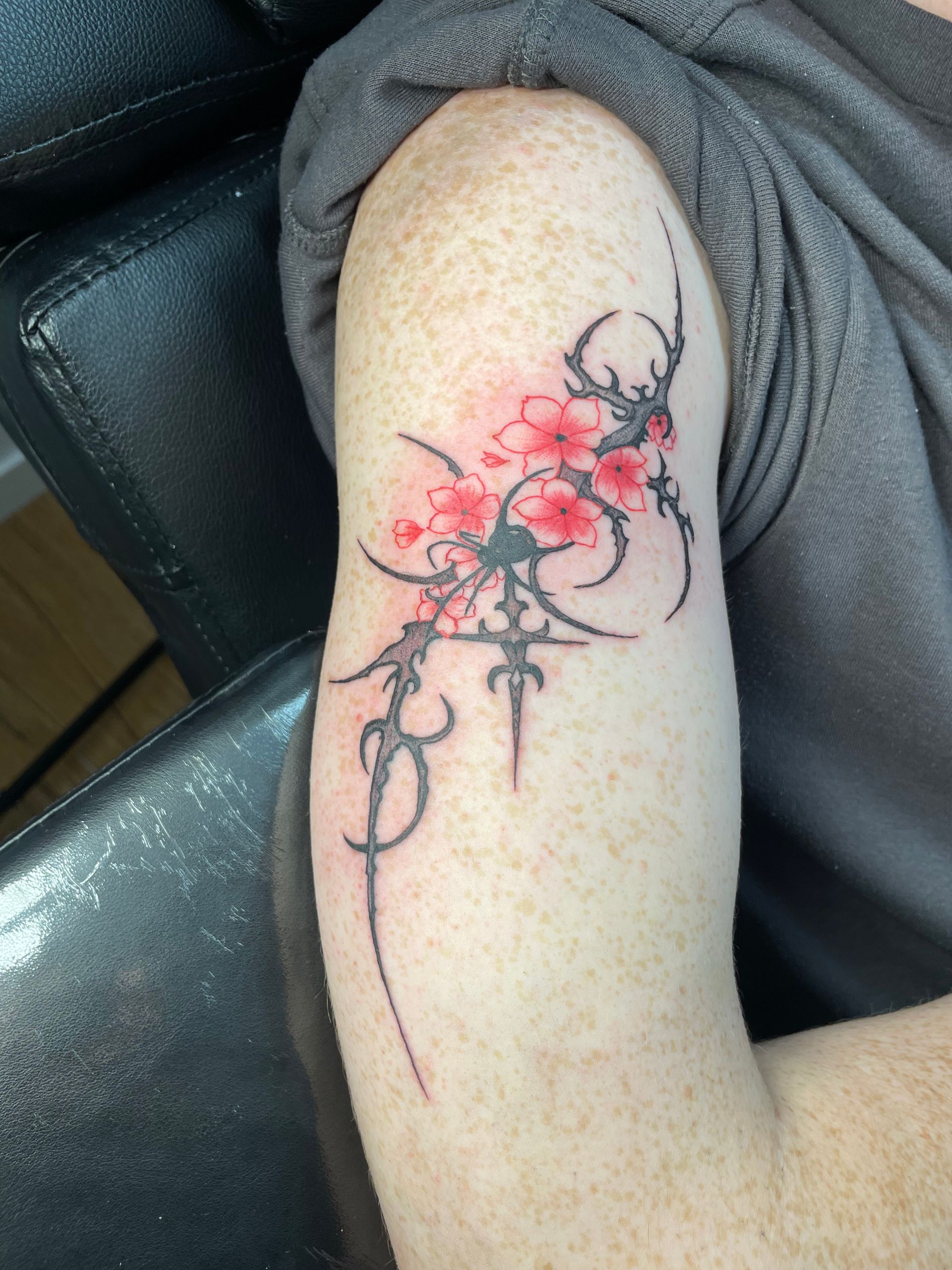 Close-up of a forearm with a red and black floral tattoo design