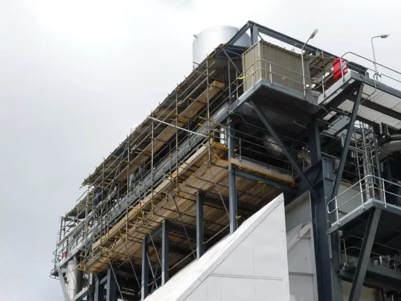 A large building with suspended scaffolding cantilevered from the top of the building