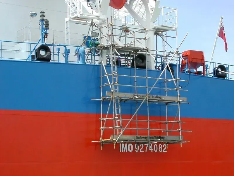 Scaffolding on the side of a large ship cantilevered off the side