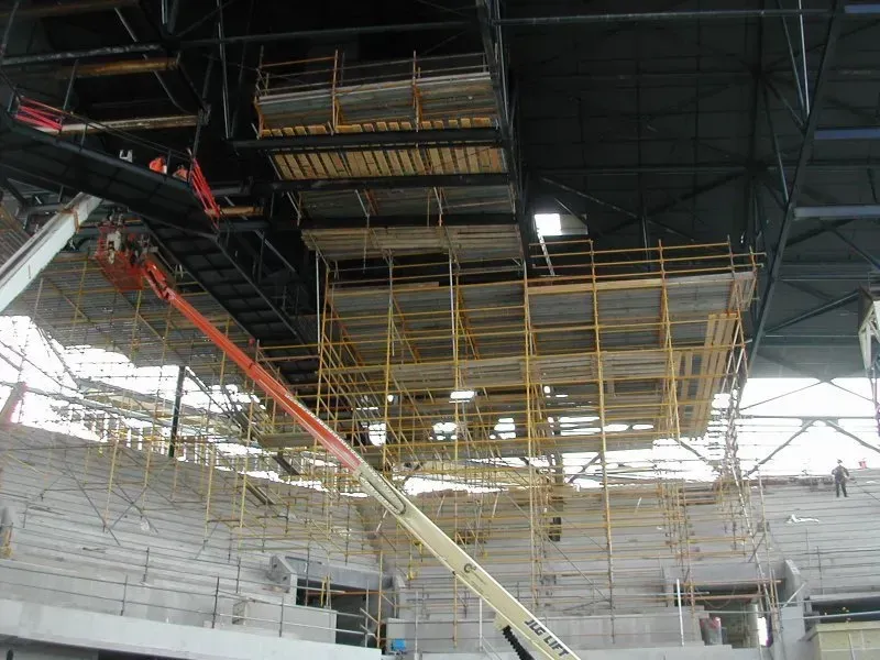 A large stadium under construction with scaffolding and a crane.
