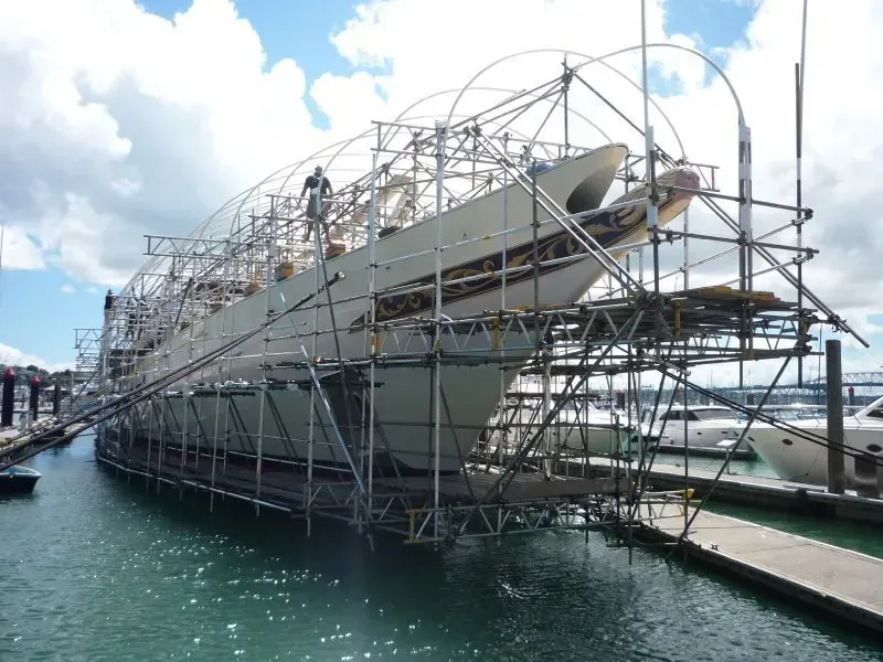 a scaffold structure over a boat prior to shrink wrap encapsulation suspended from the boat on the water