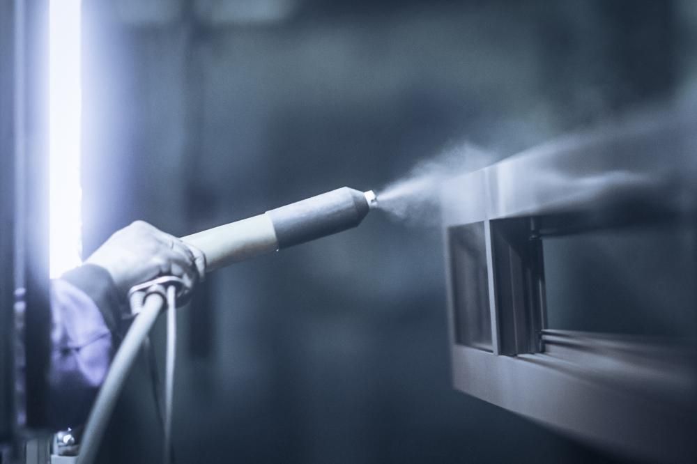 A Person is Spraying Powder Paint on a Piece of Metal — Alamo Powder Coaters in Bowral, NSW