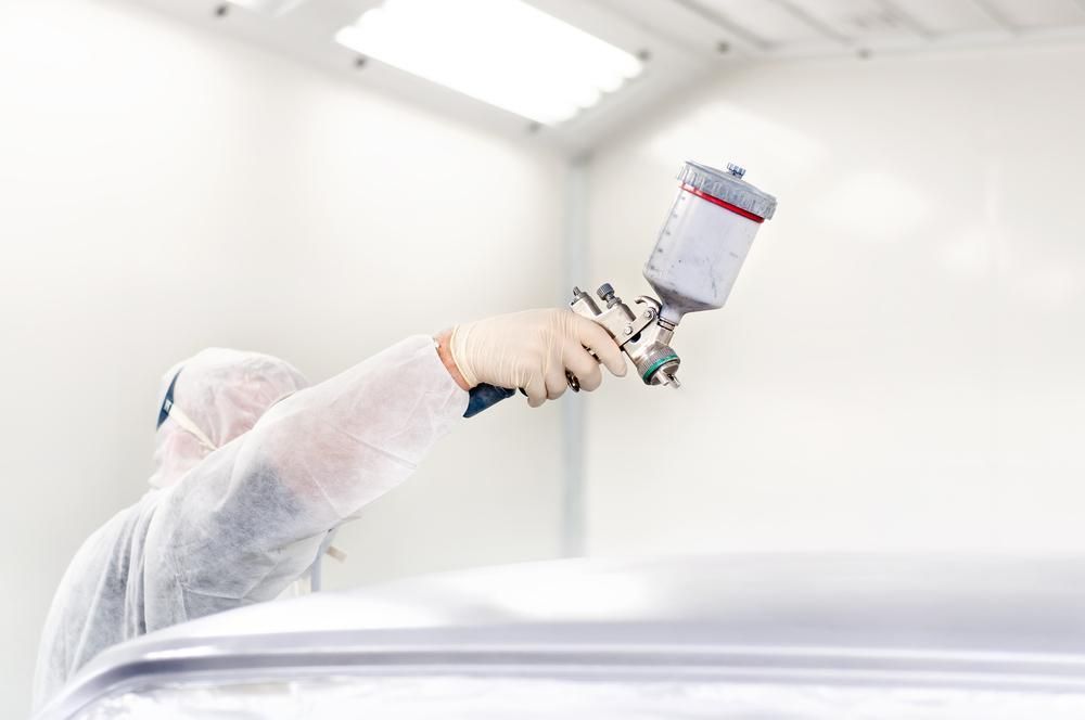 A Man is Painting a Car in a Paint Booth — Alamo Powder Coaters in Nowra, NSW