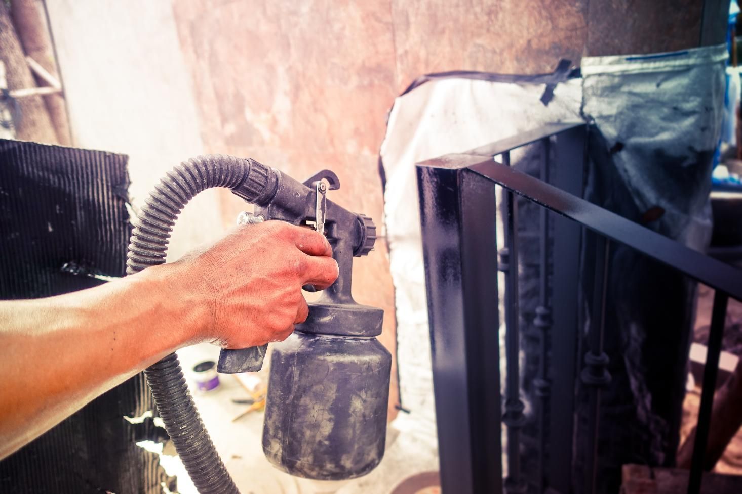 A Man is Spray Painting the Metal With Black Coating — Alamo Powder Coaters in Mittagong, NSW
