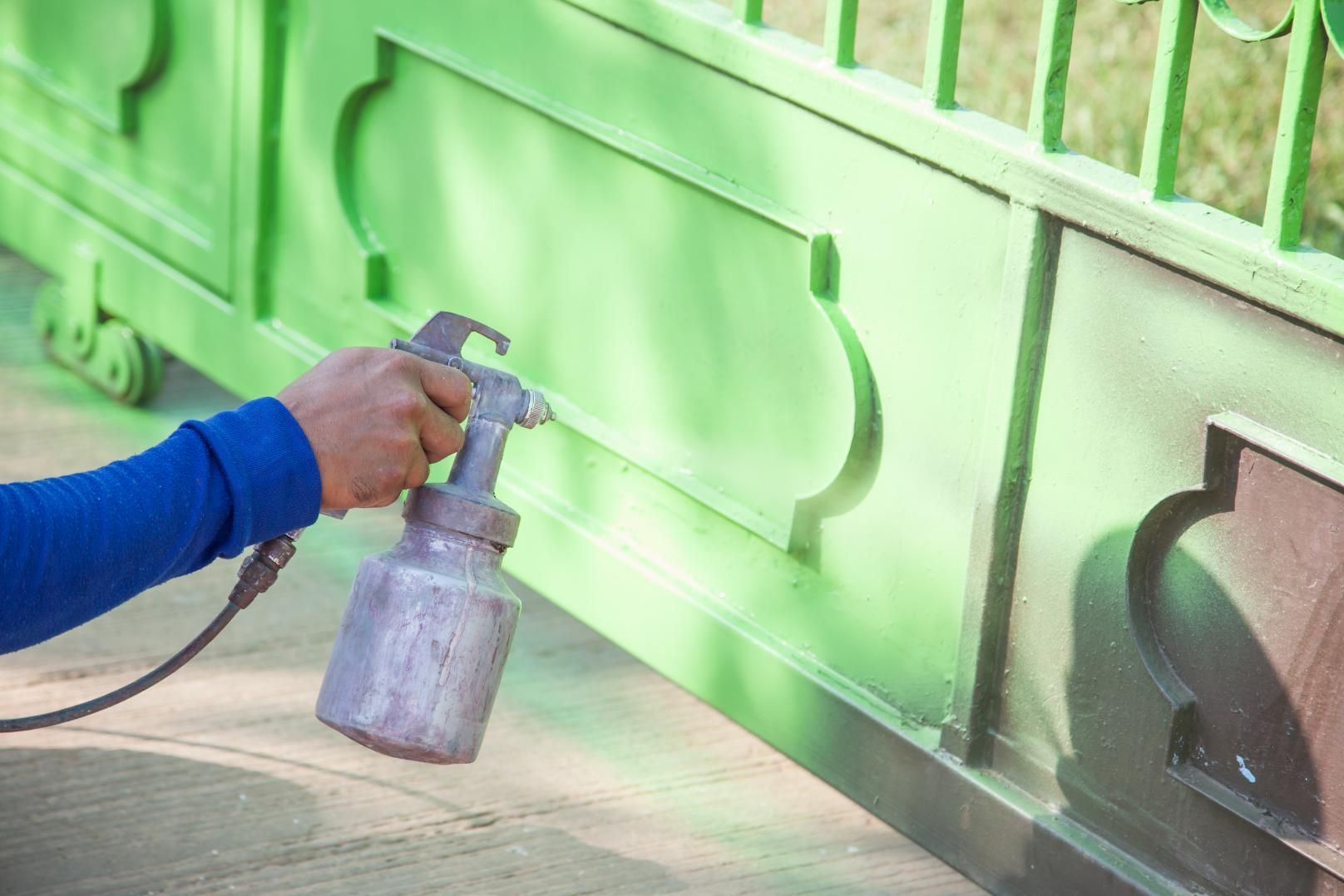 A Person is Spraying Paint on a Green Gate — Alamo Powder Coaters in Heathcote, NSW