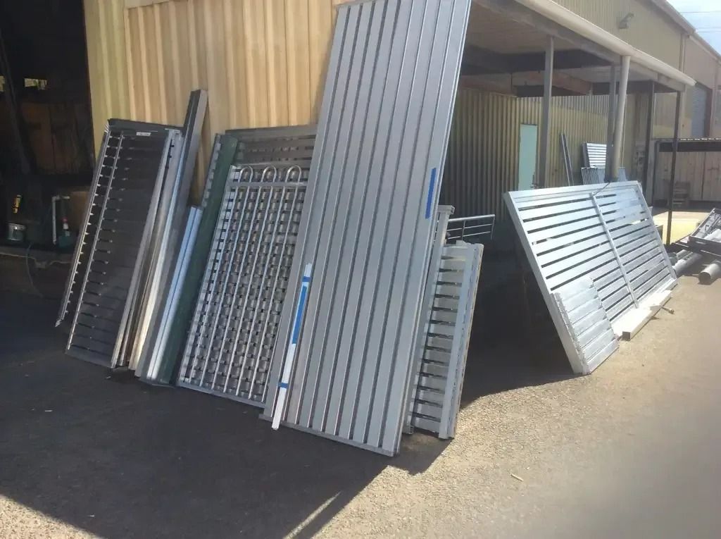 A Bunch of Metal Pieces Are Stacked on Top of Each Other in Front of A Building — Alamo Powder Coaters in Unanderra, NSW