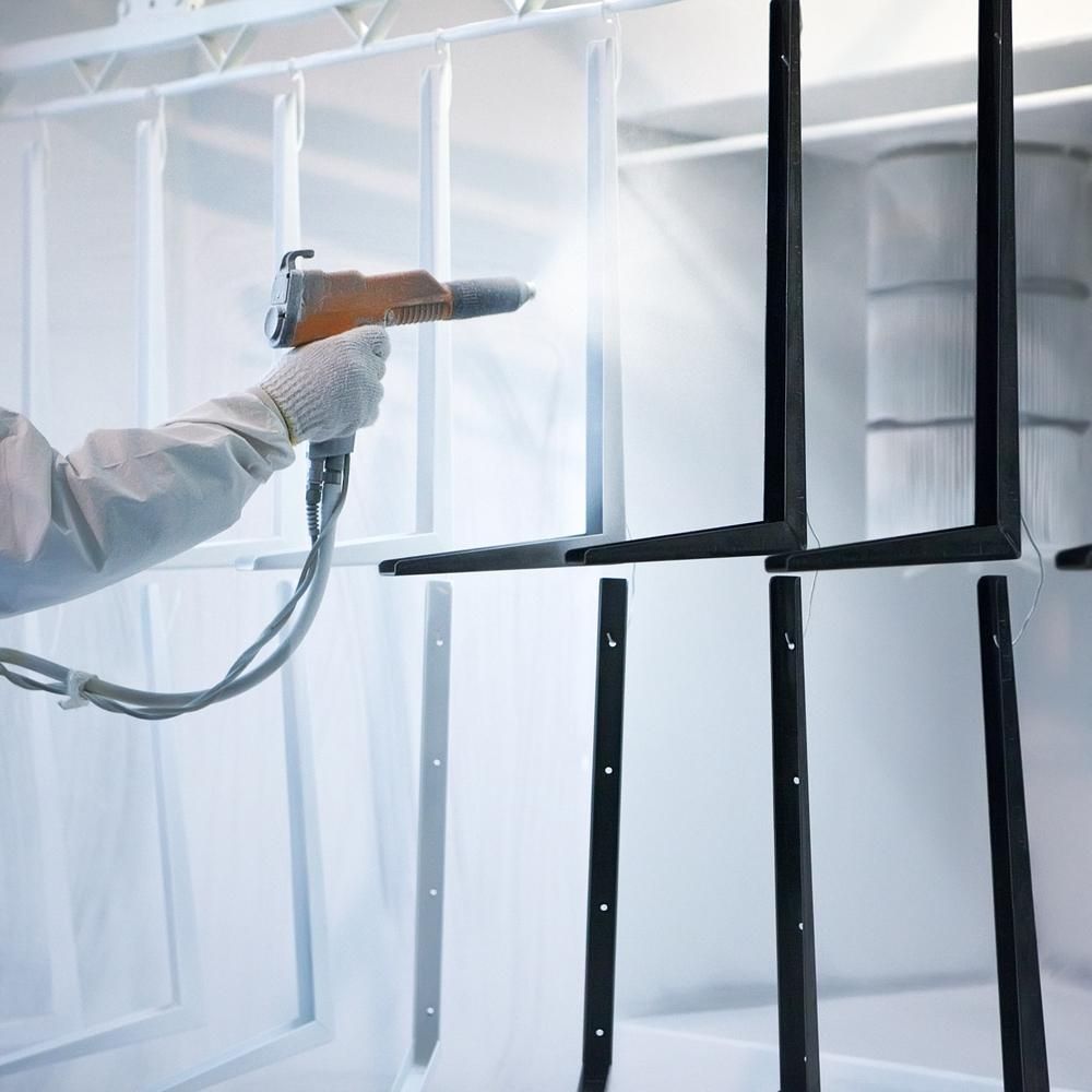 A Man is Spray Painting a Metal With White Coating — Alamo Powder Coaters in Moss Vale, NSW