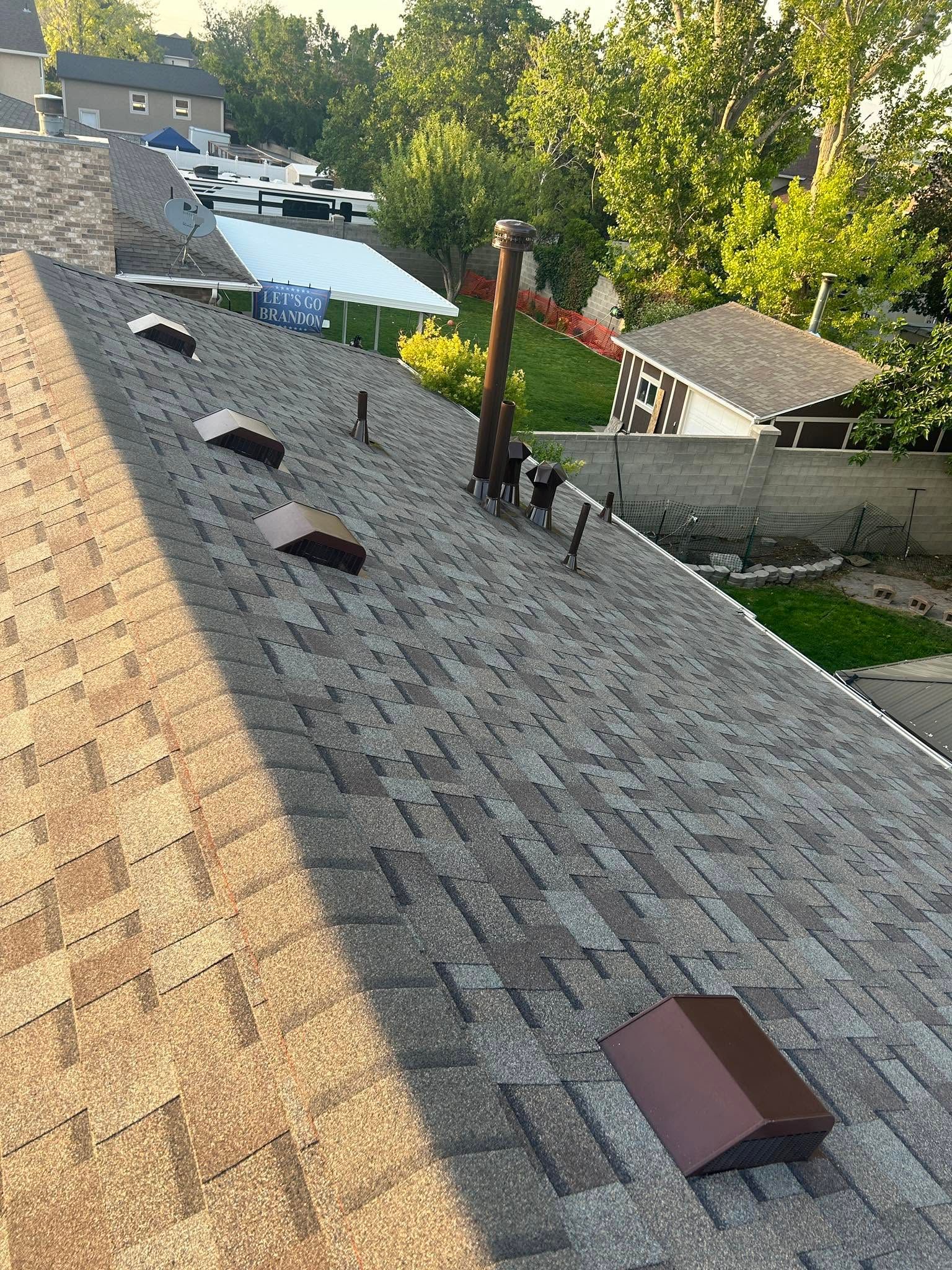 Steep shingled roof with several vents, overlooking a residential backyard and pool.