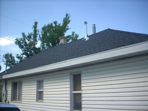 Single-story white house with dark shingled roof under a blue sky
