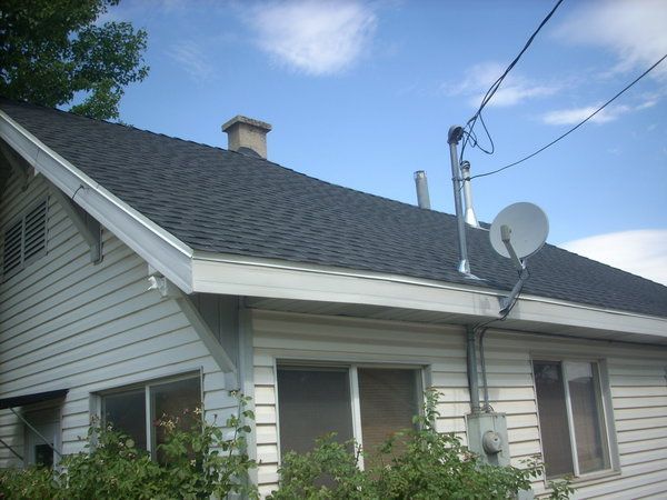 White house roof with satellite dish and chimney under a blue sky