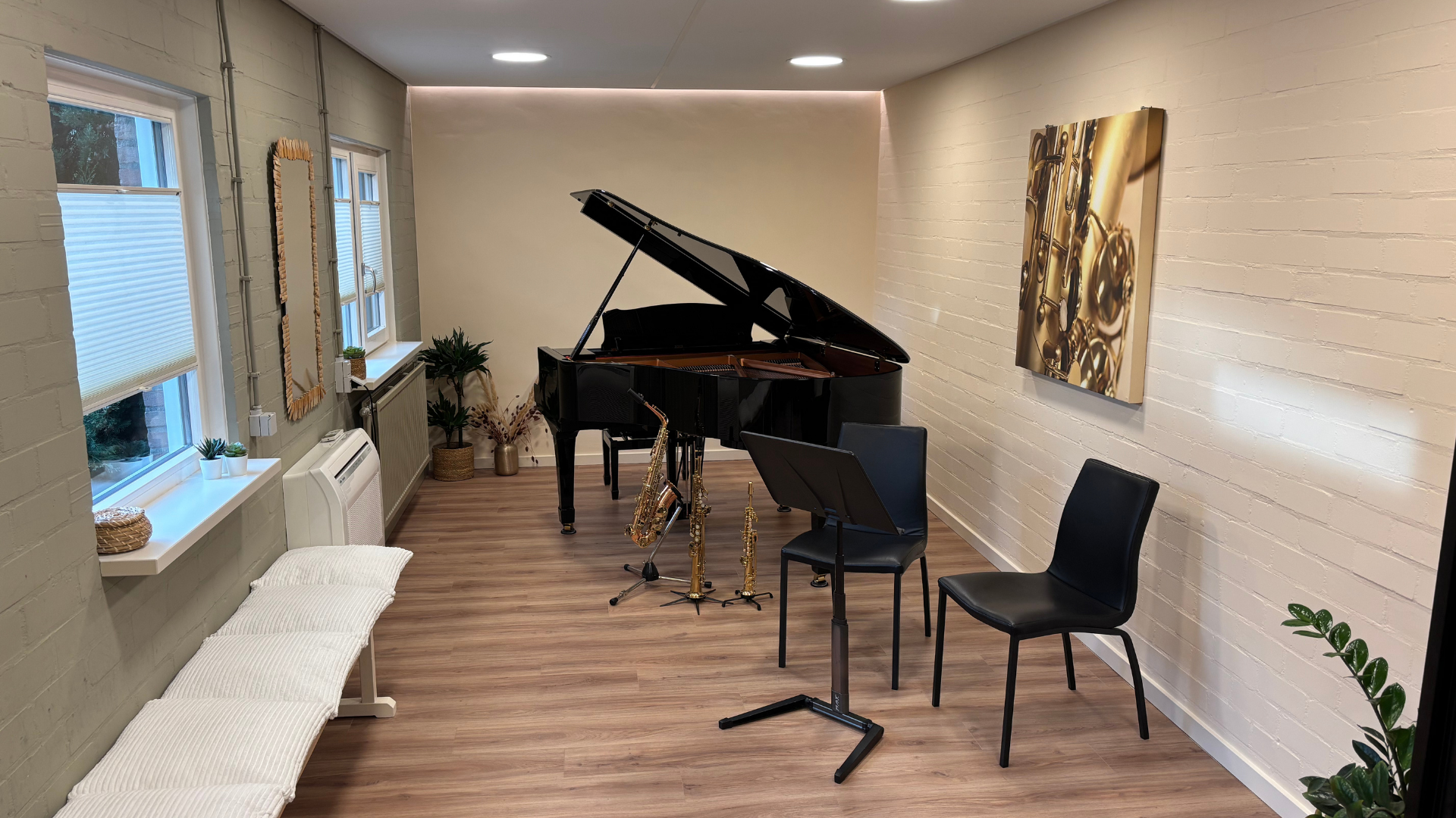 Een muziekkamer met een vleugel, lessenaars, stoelen en kunstwerken aan de muur.