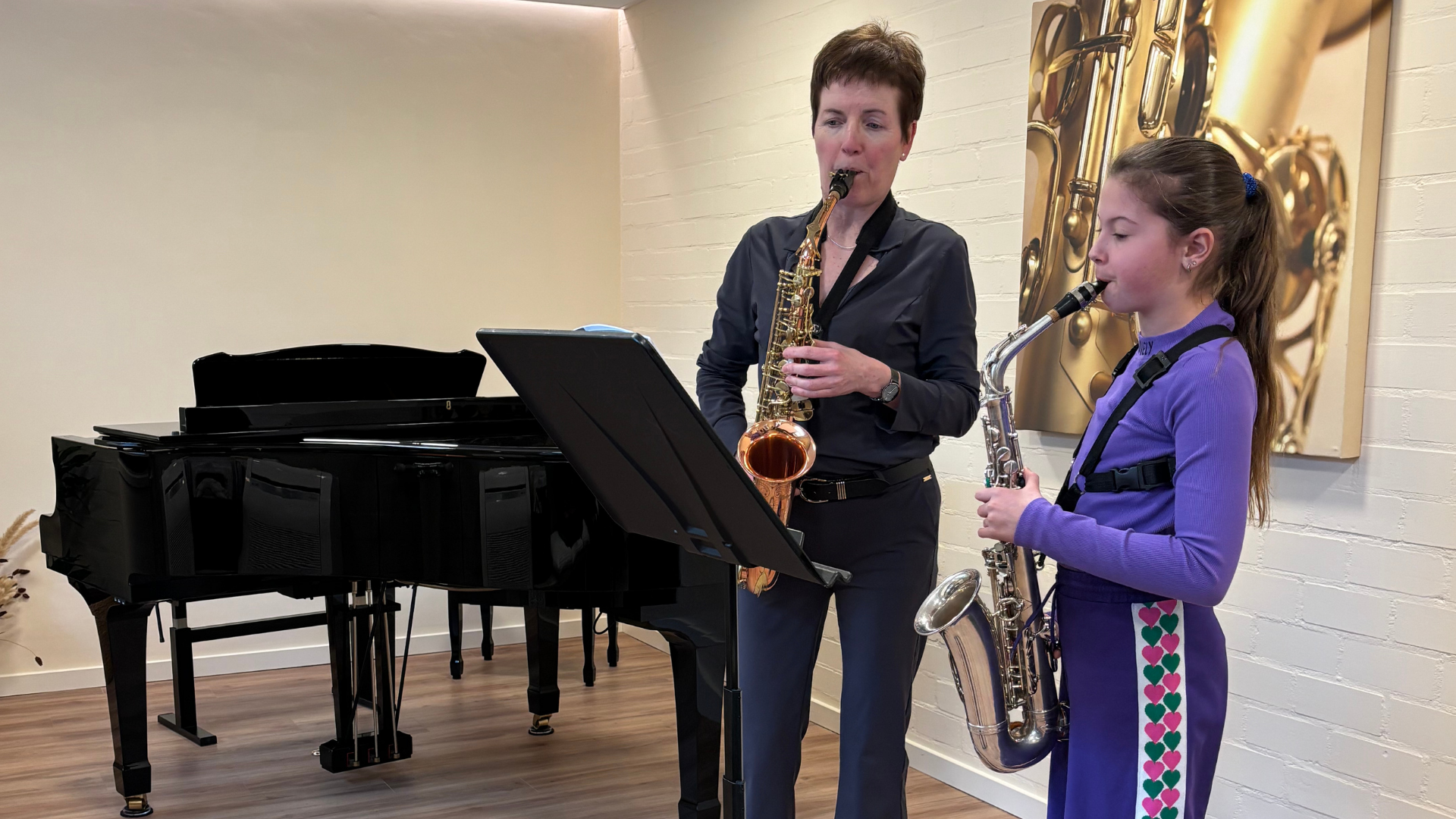 Twee mensen spelen saxofoon in een muziekkamer met een piano.