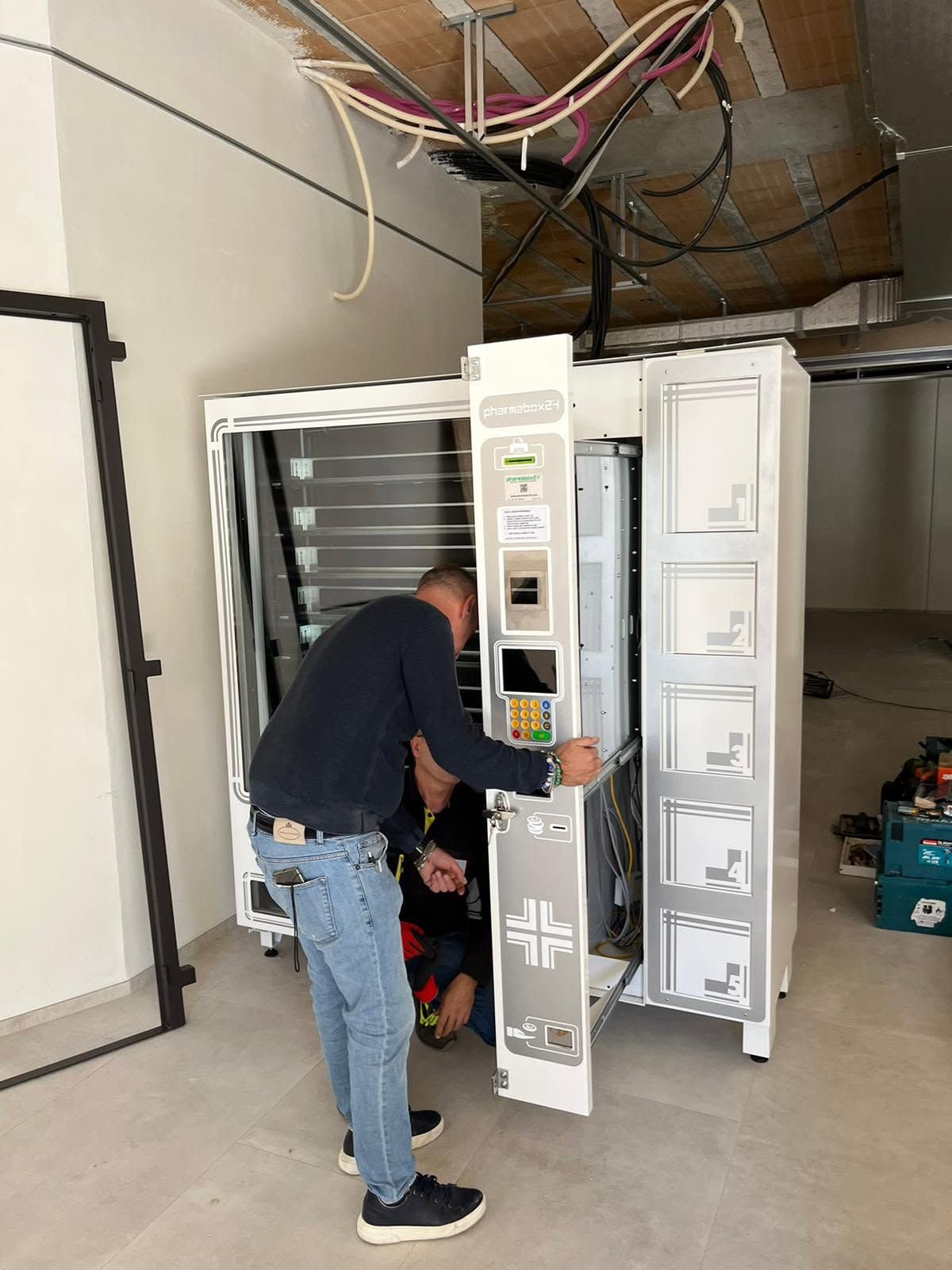 Un operaio scarica un grande armadio o un distributore automatico in un garage con la porta aperta.
