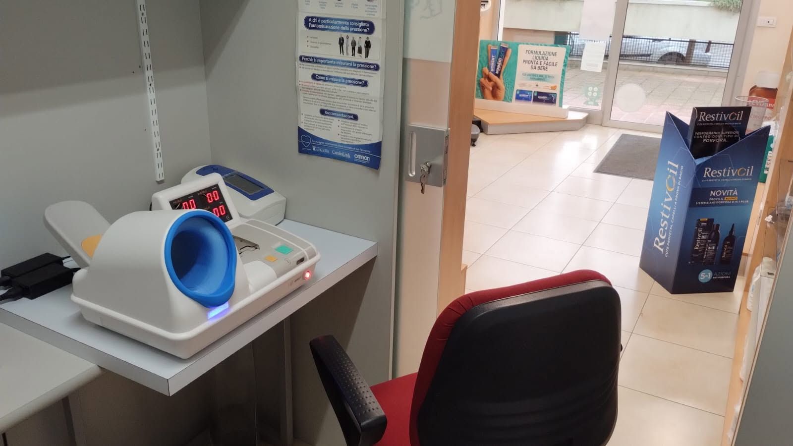 Scrivania con megafono blu, sedia rossa e porta che conduce a un corridoio piastrellato.