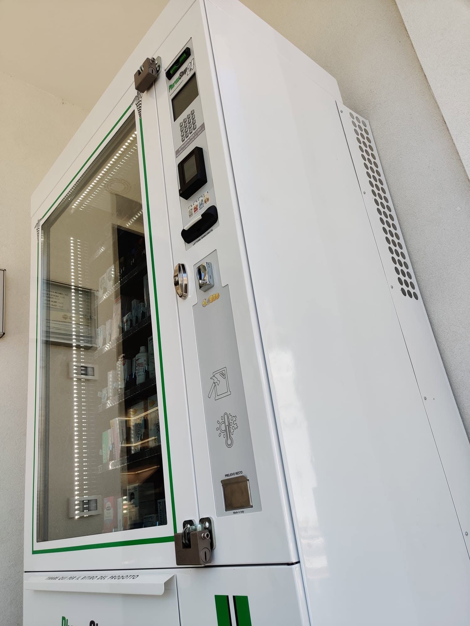 Distributore automatico o armadietto bianco con sportello in vetro e pannello di controllo addossato a una parete