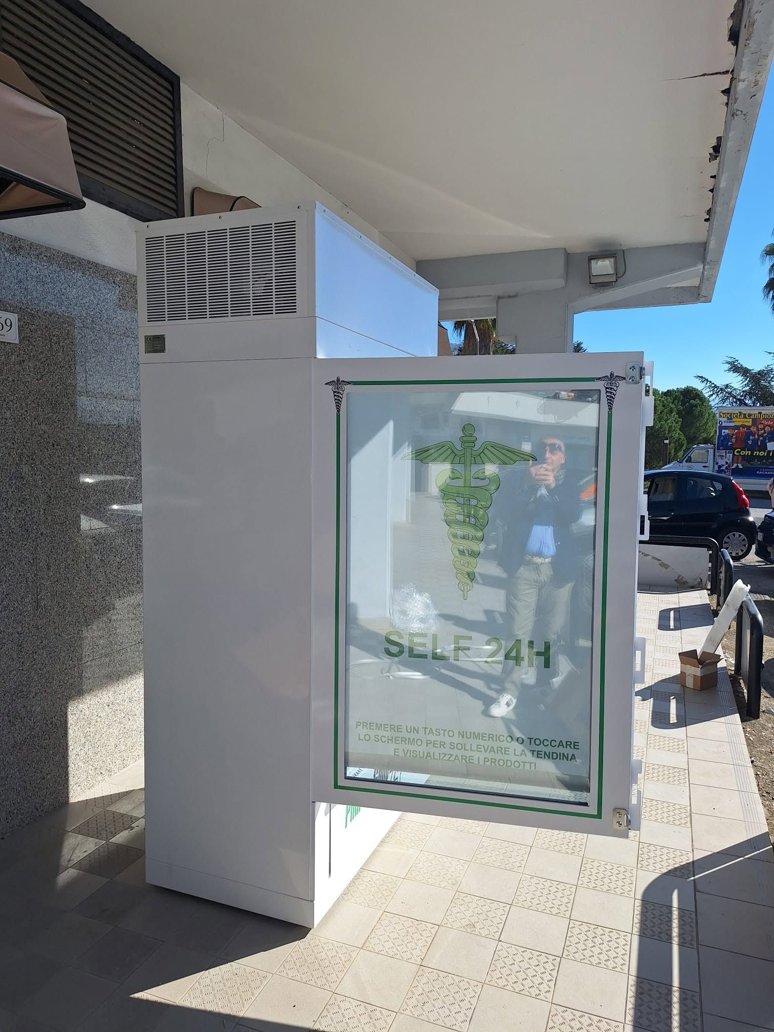Vetrina refrigerata con frontale in vetro all'esterno di un negozio su un marciapiede soleggiato