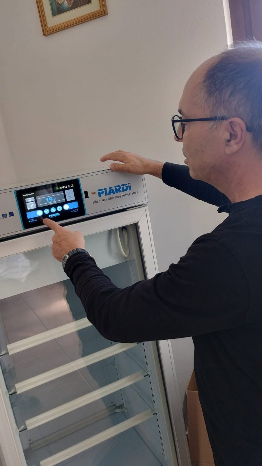 Uomo che utilizza un pannello di controllo touchscreen su una macchina bianca in una stanza con una finestra