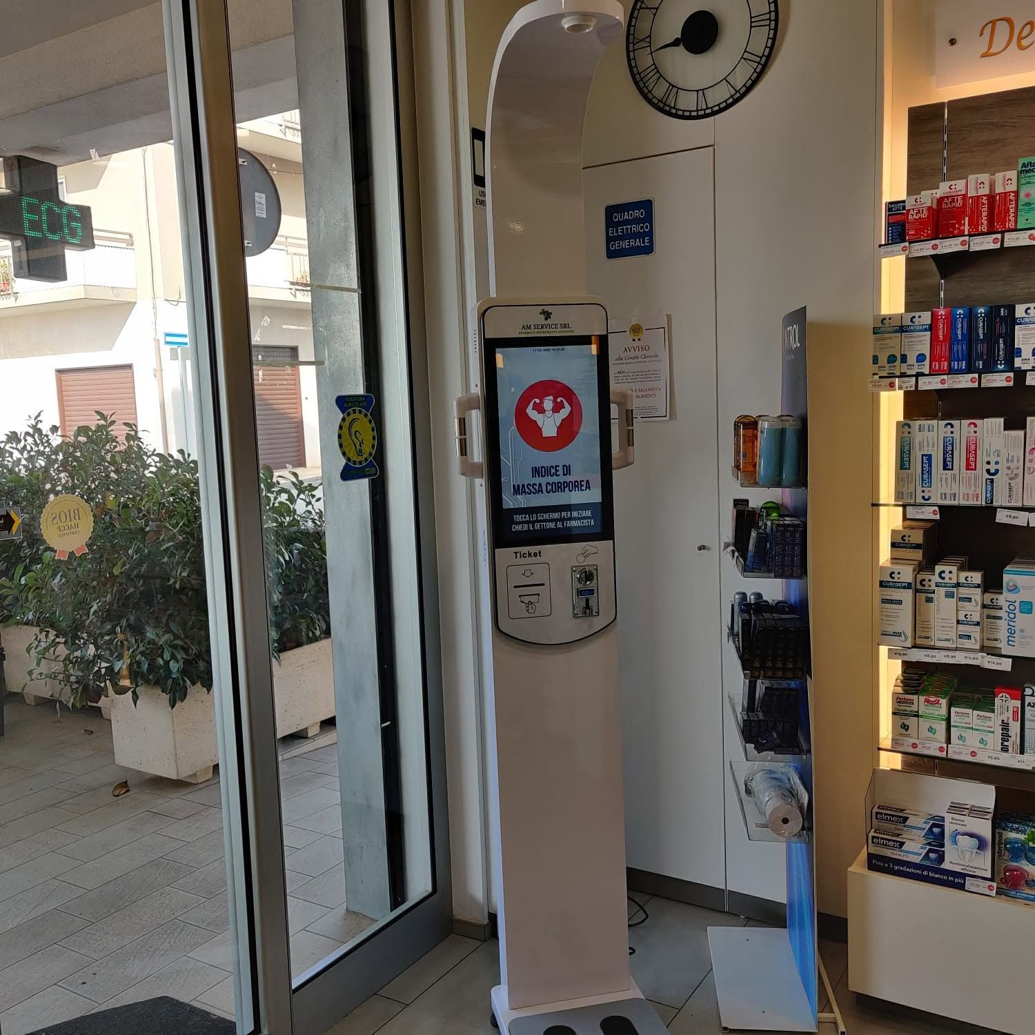 Ingresso del negozio con dispenser di gel igienizzante per le mani posizionato accanto a un espositore di prodotti.