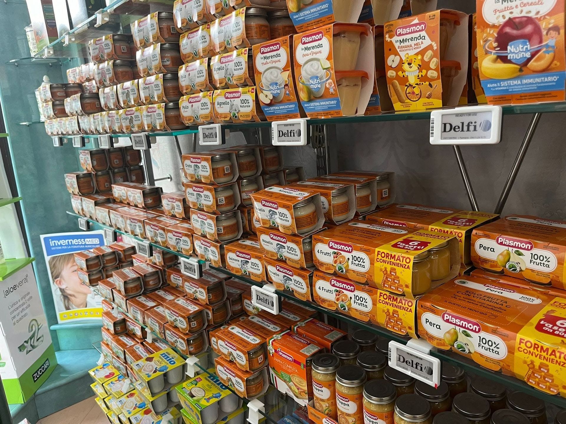 Scaffali pieni di vari prodotti alimentari confezionati in una corsia di un supermercato.