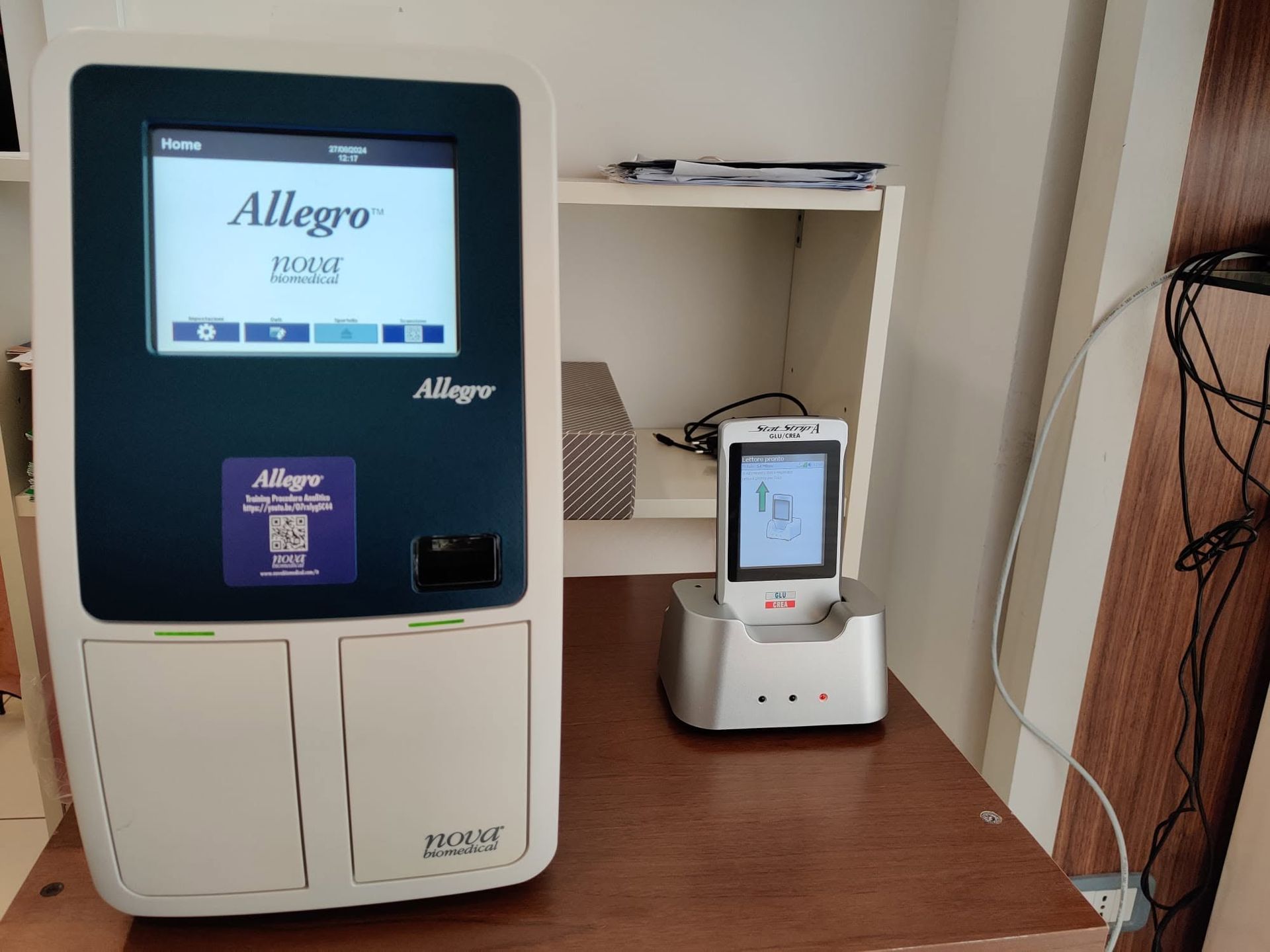 Dispositivo medico Allegro e piccola unità touchscreen su un tavolo di legno in un ambiente clinico.