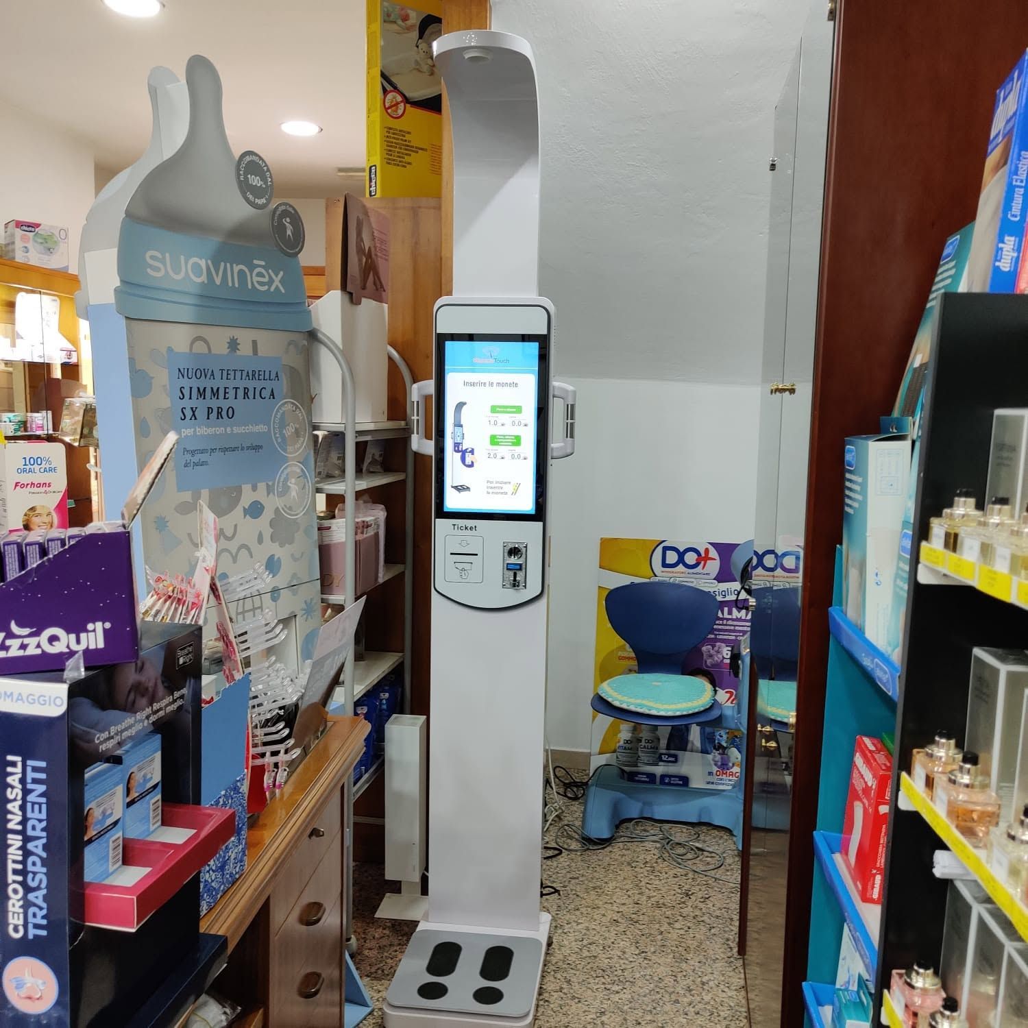 Corridoio del negozio con un chiosco self-service posizionato al centro tra gli scaffali dei prodotti.