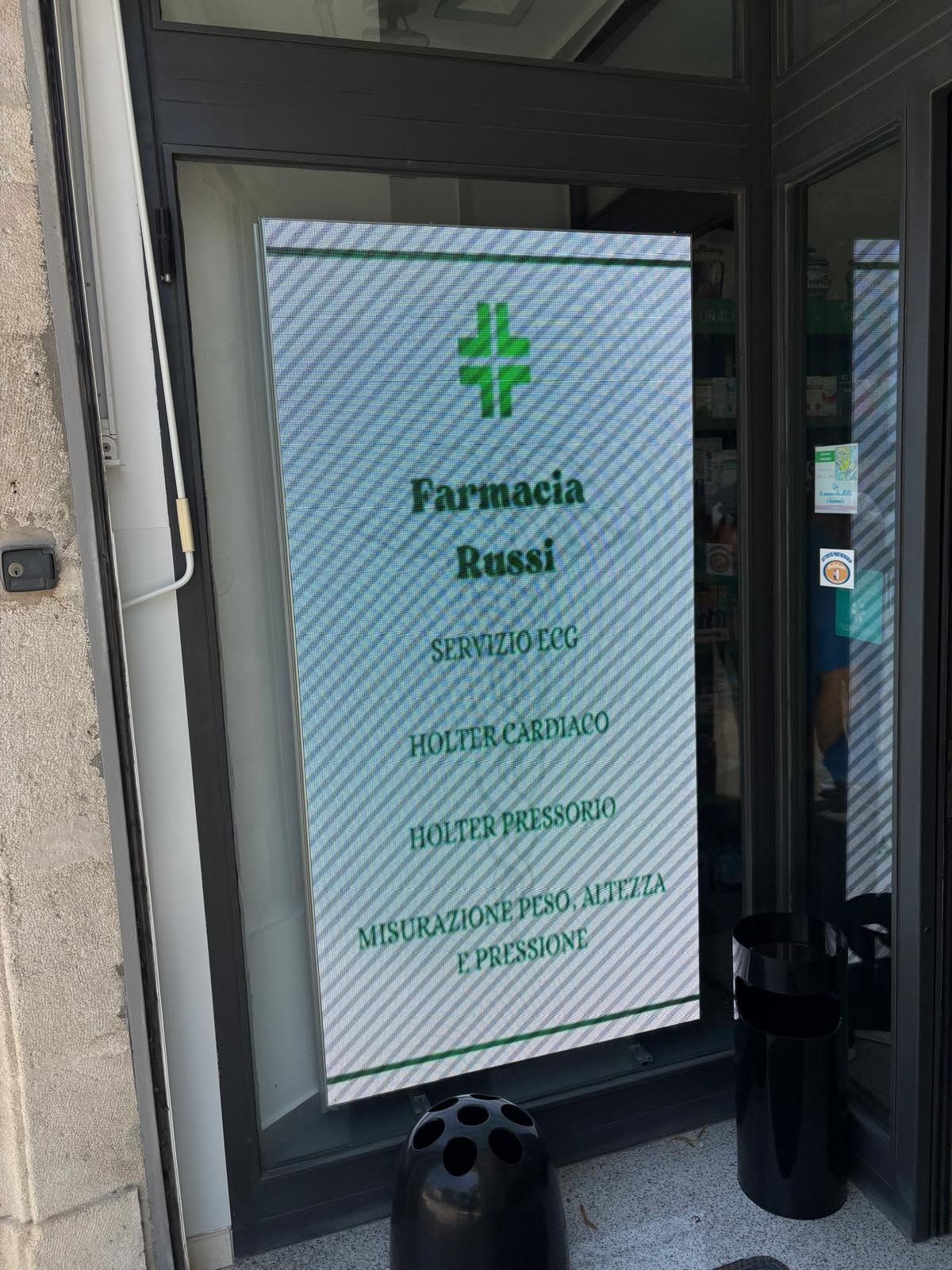 Porta a vetri della farmacia con croce verde e insegna