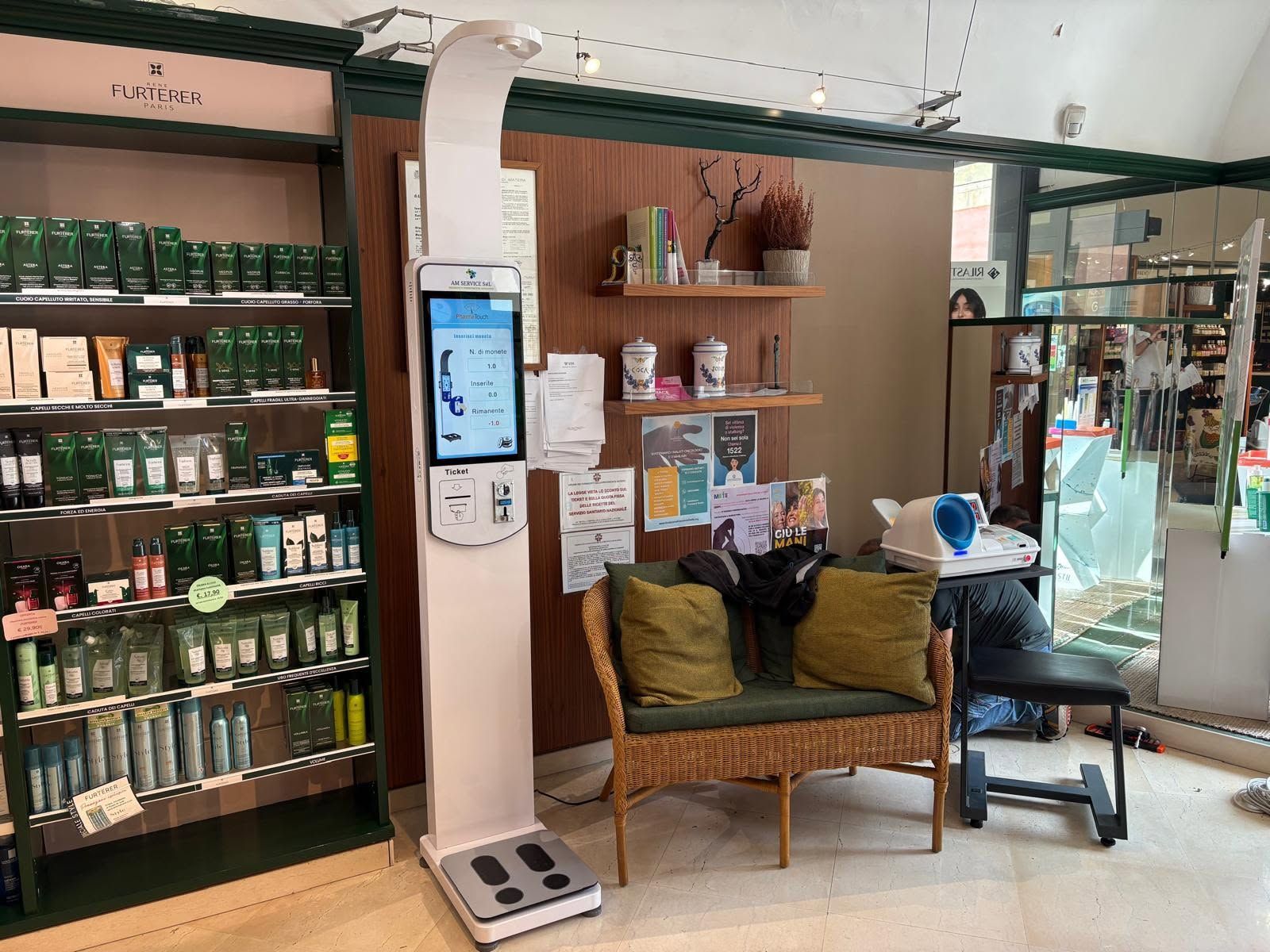 Accogliente caffetteria in stile boutique con scaffali pieni di barattoli, una sedia in vimini e un chiosco digitale vicino al bancone.