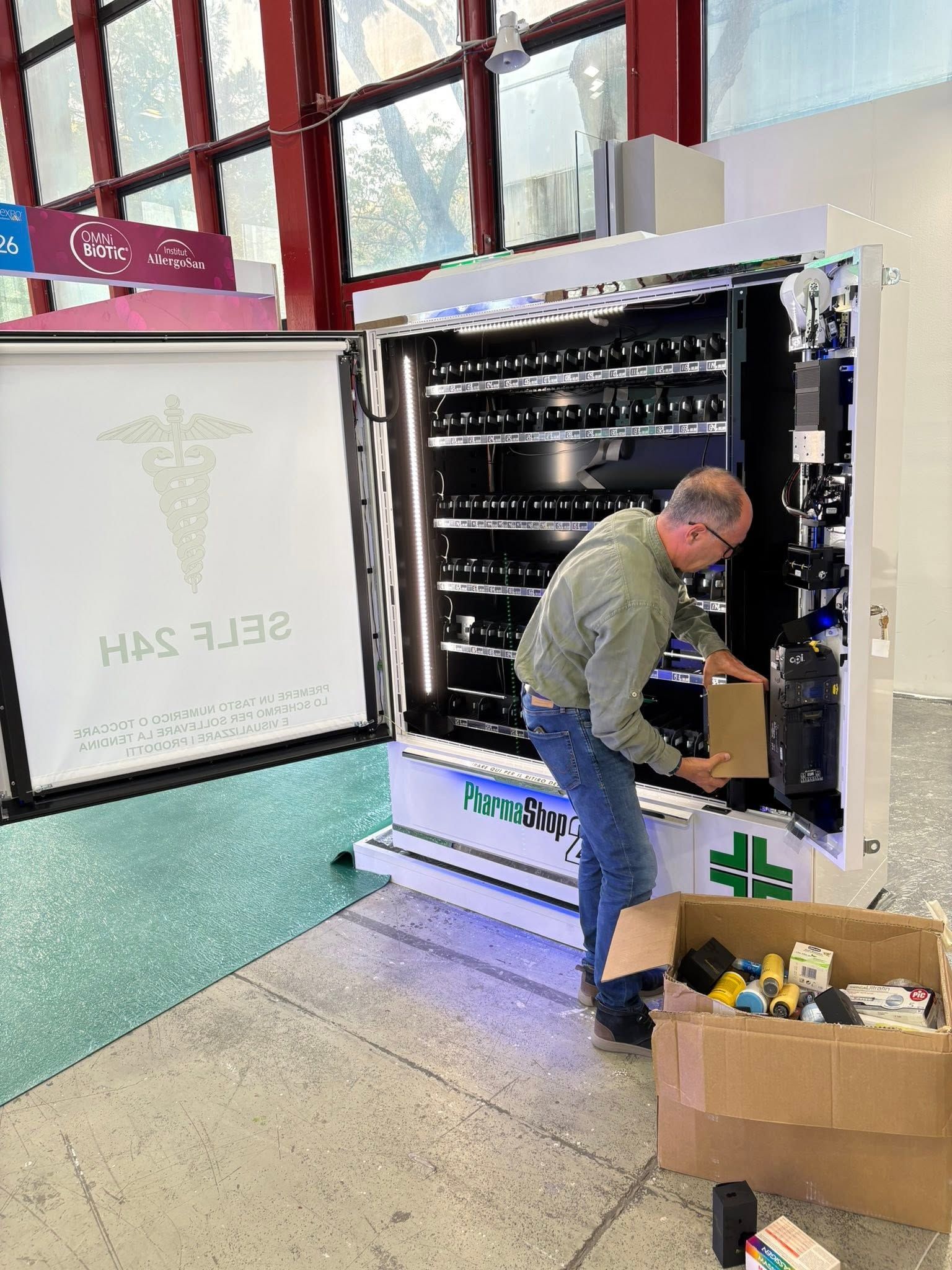 Un uomo carica delle casse in un espositore refrigerato in una corsia di un negozio.