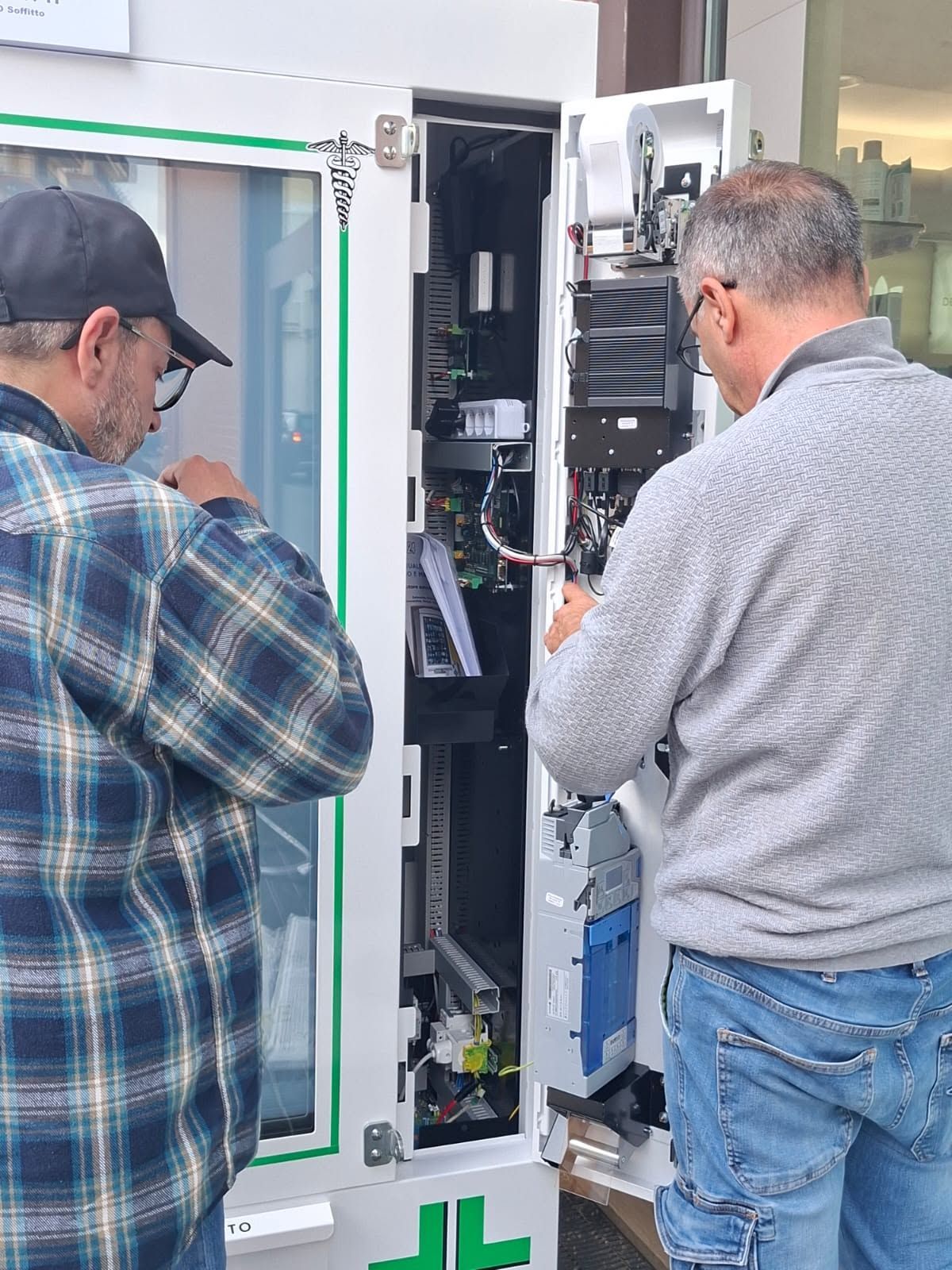 Due tecnici ispezionano un quadro elettrico aperto all'aperto.