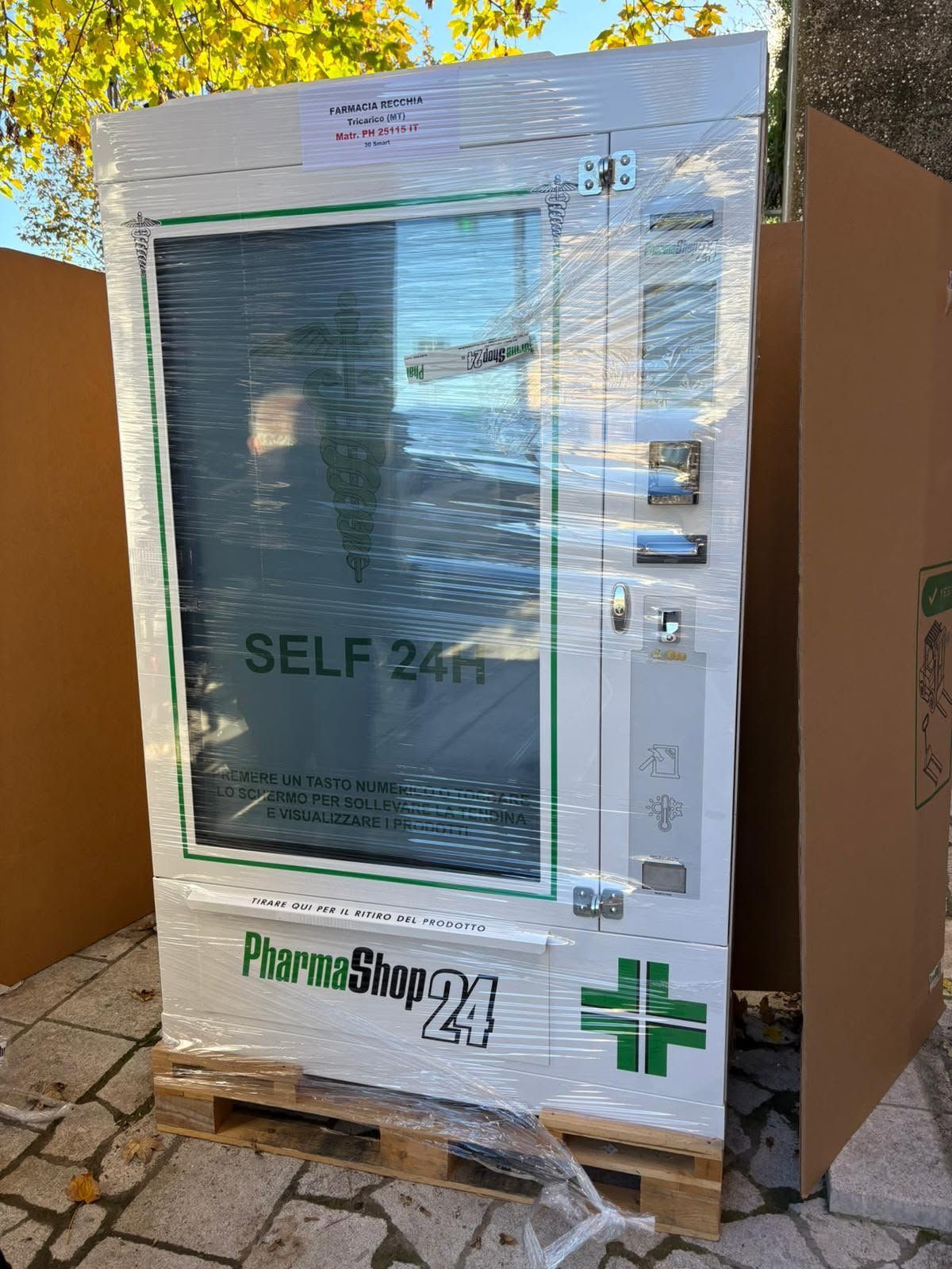 Chiosco farmacia self-service bianco con porta in vetro e insegna verde