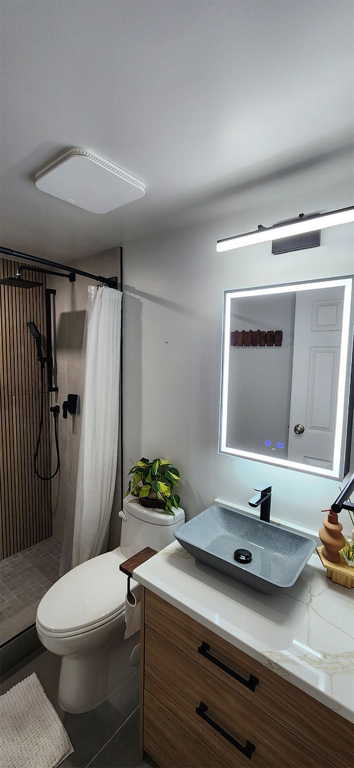Modern bathroom with shower, toilet, vanity sink, mirror, and wood accents