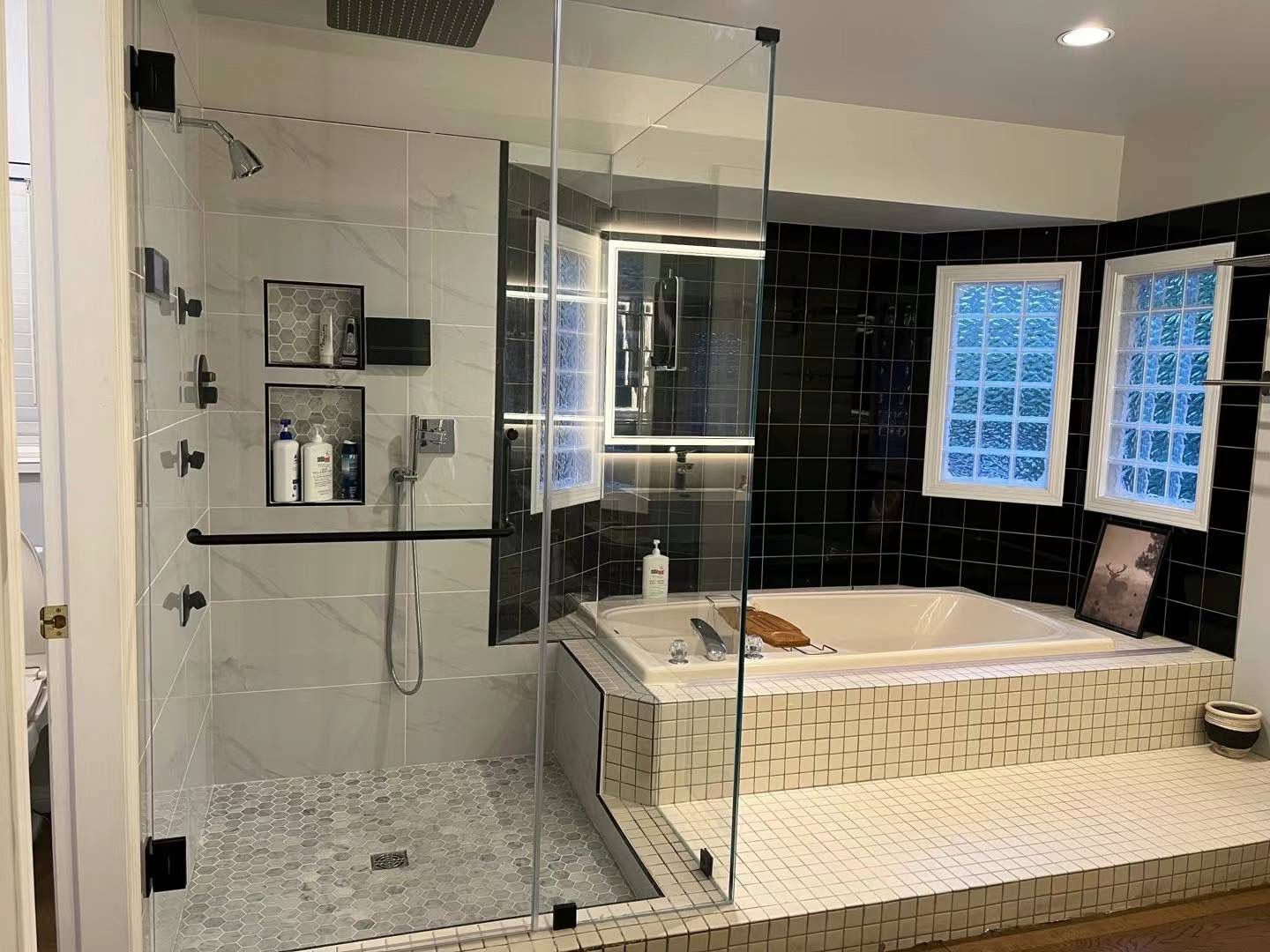 Modern bathroom with glass shower, soaking tub, dark tile accent wall, and frosted windows