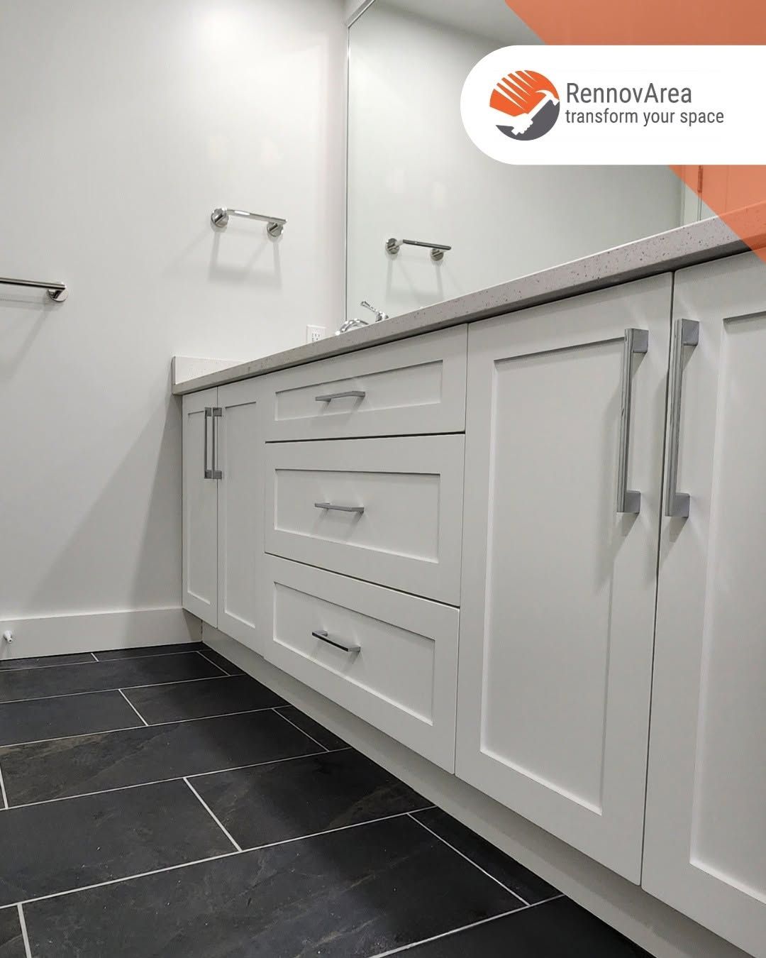 White bathroom vanity with drawers and cabinet doors, chrome handles, and dark tiled floor in a clean room.