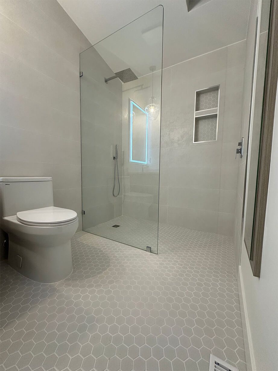 Modern bathroom with glass shower, wall-mounted toilet, and light hex tile floor
