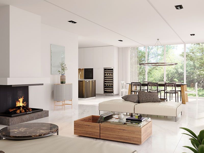 Modern open-plan living room with a black fireplace, white furniture, and large windows overlooking greenery