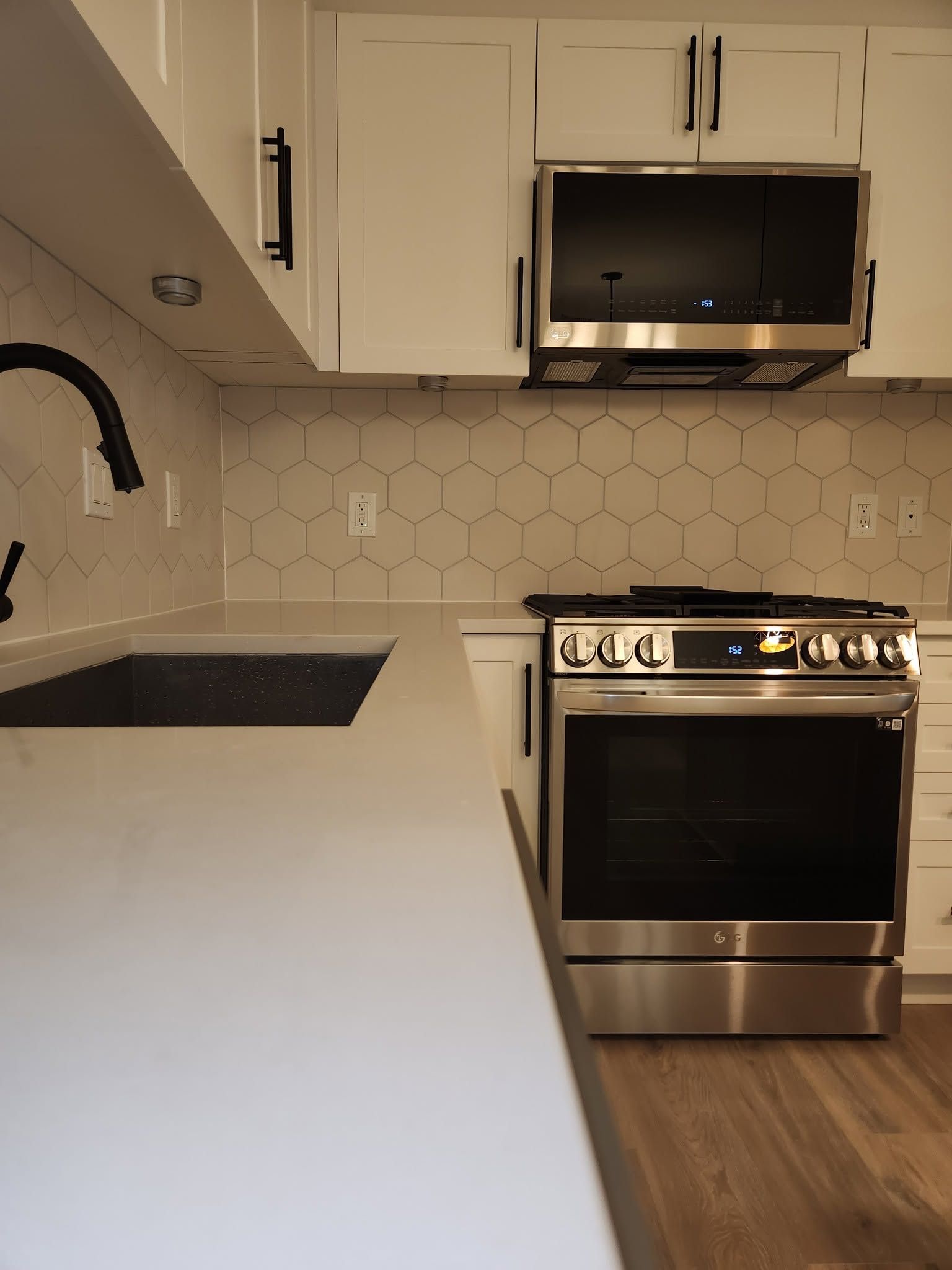 Modern kitchen with white cabinets, black stove, sink island, and wood flooring