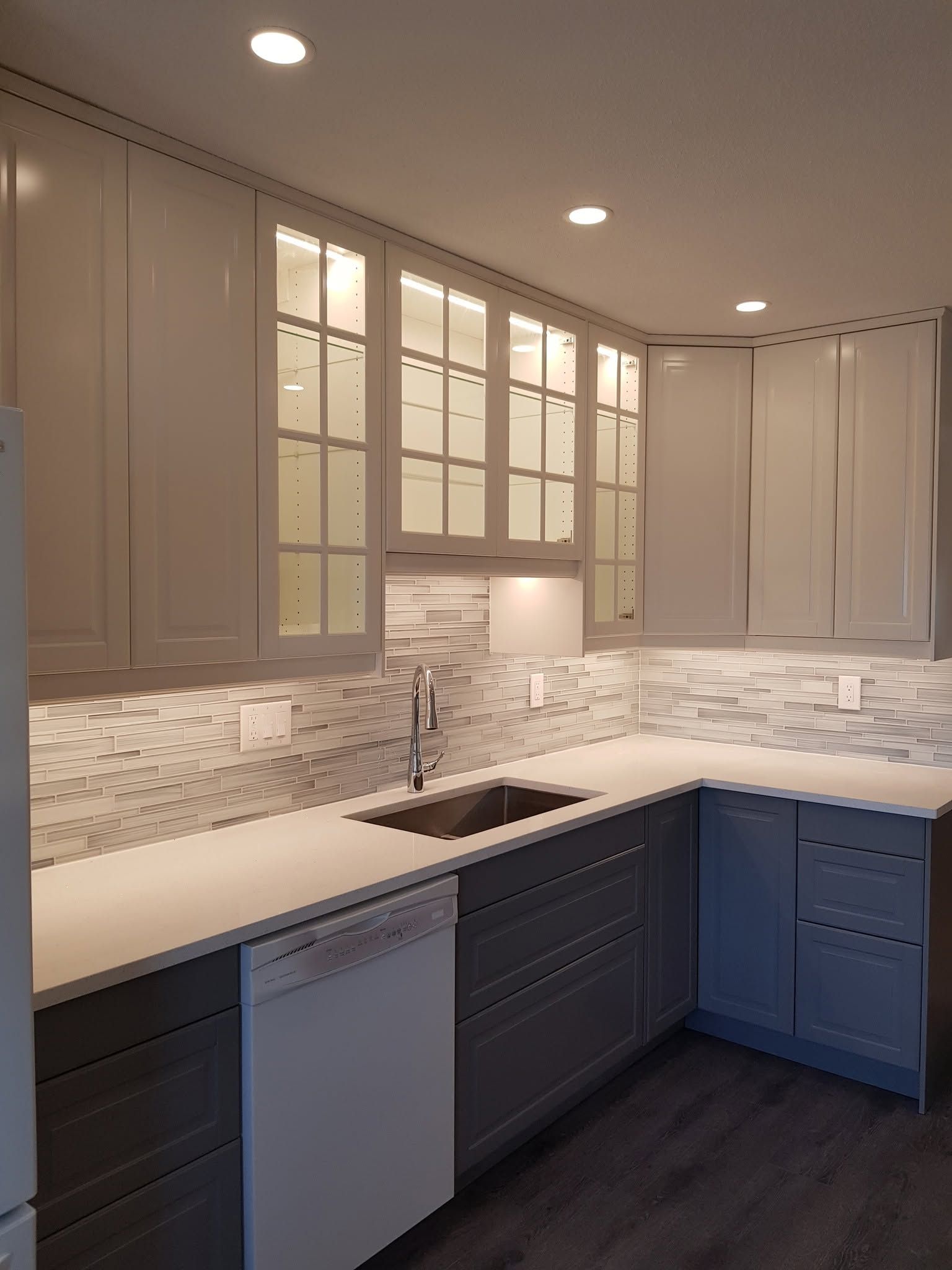 Modern kitchen with white cabinets, mosaic backsplash, white countertops, and dark lower cabinets