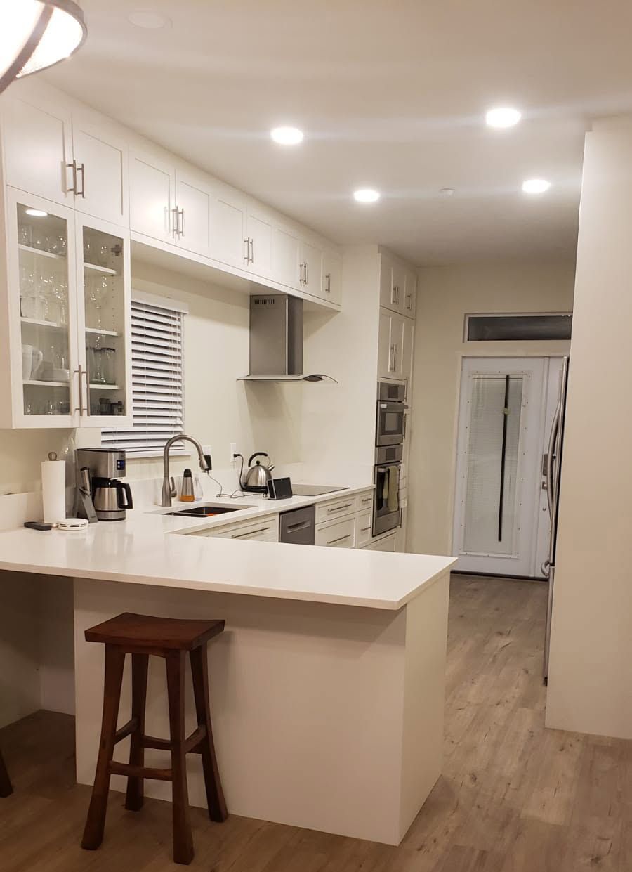 Bright modern kitchen with white cabinets, island, barstool, and stainless appliances