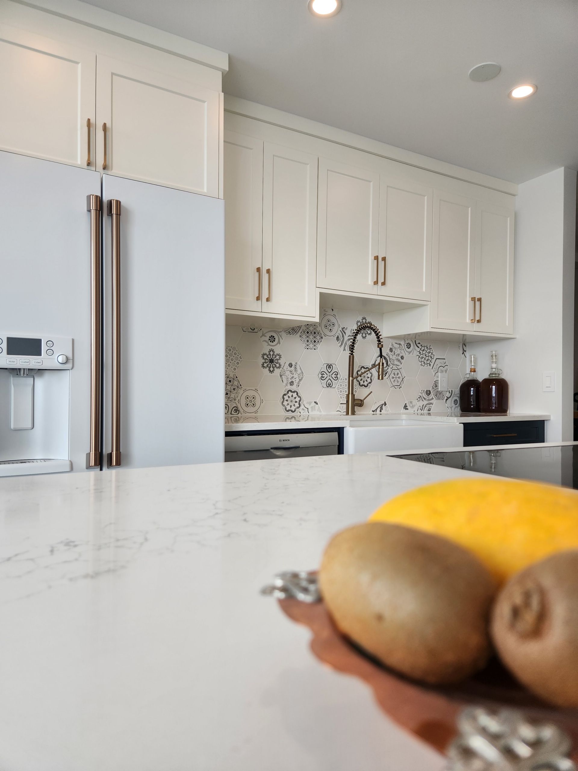 Modern white kitchen with marble island and fruit bowl in the foreground